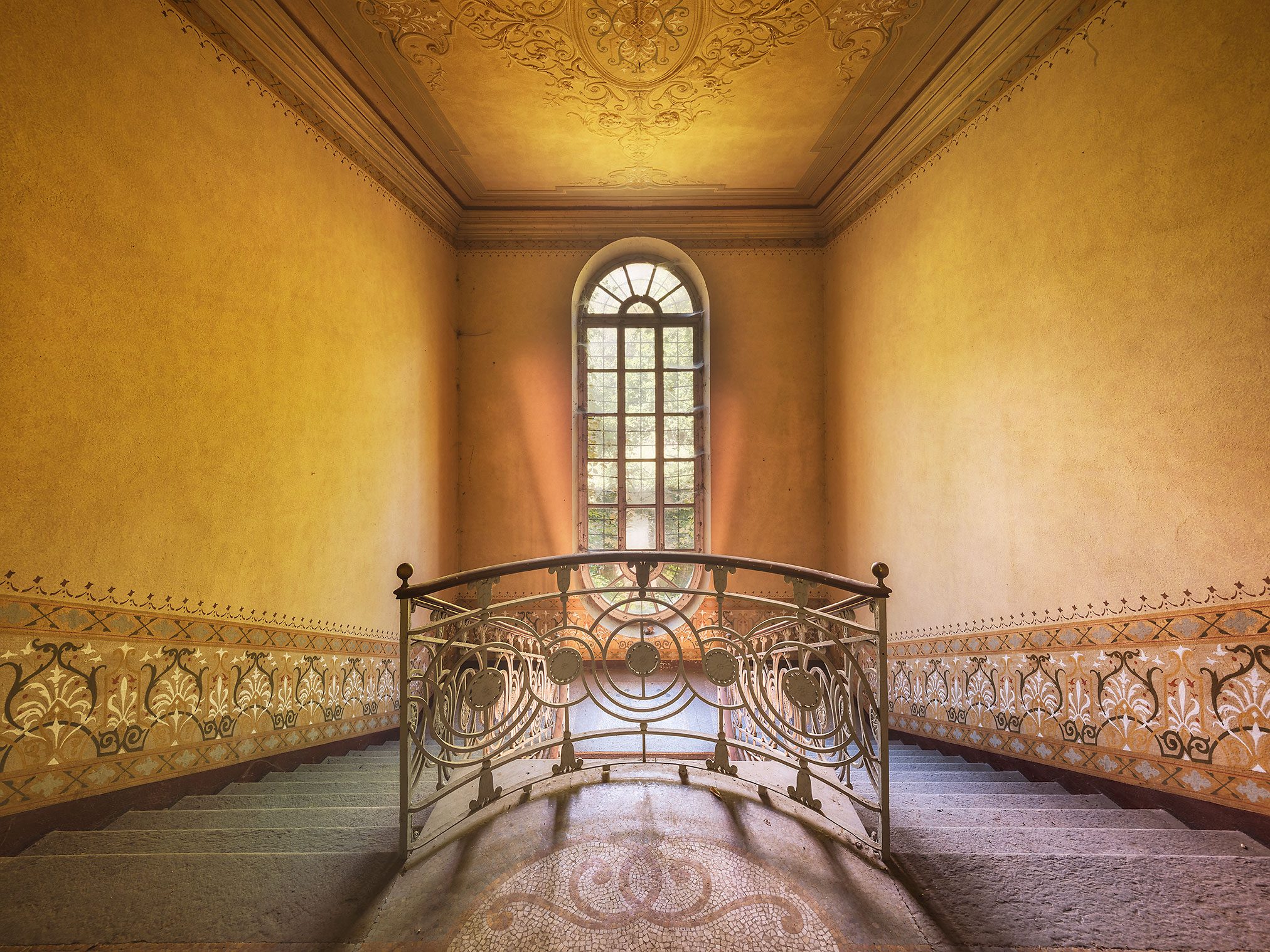 Curved staircase with a wrought-iron railing in an abandoned villa in Piedmont, Italy
