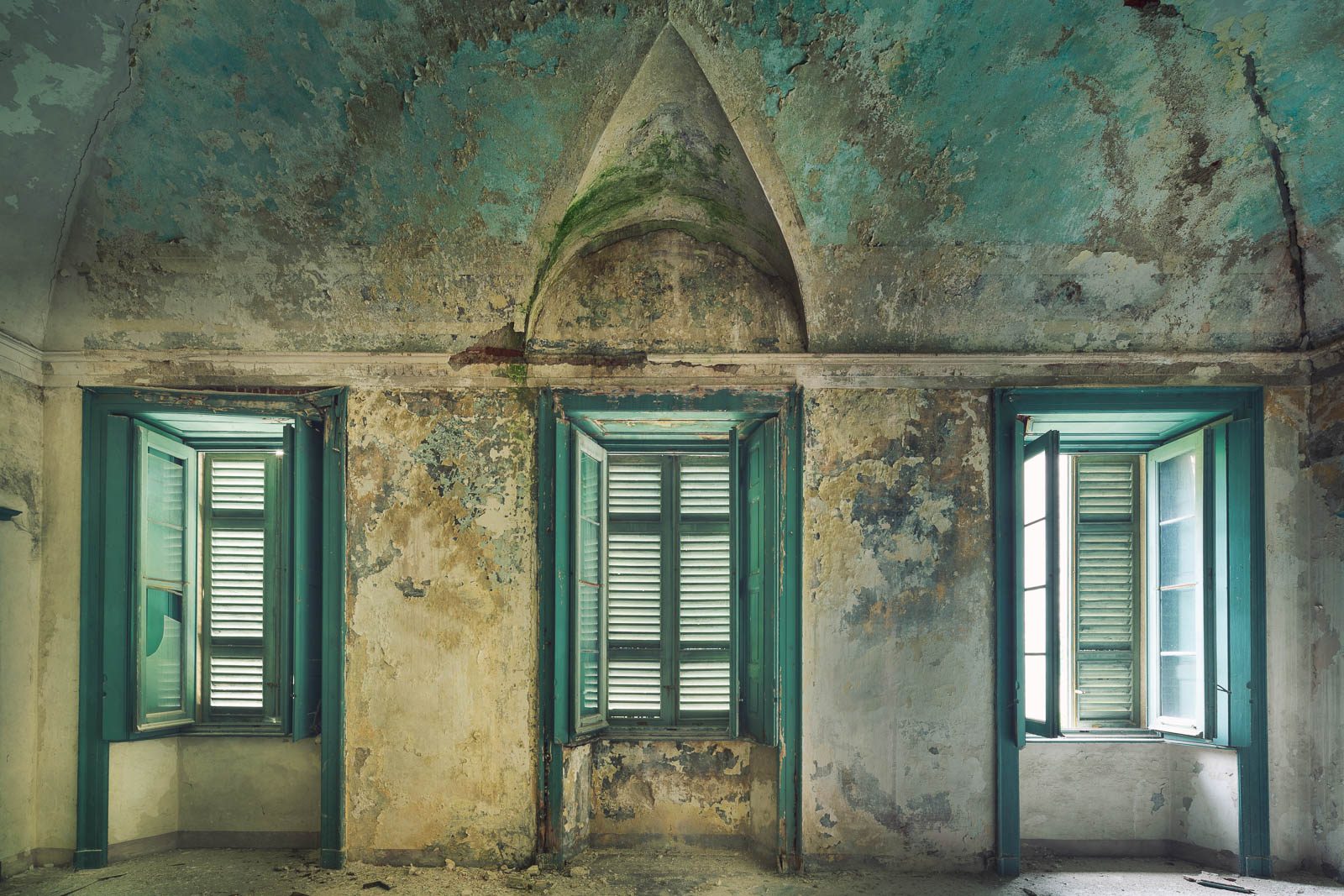 Raum mit türkisfarbener Wandfarbe und grünen Fensterläden in einem verlassenen Kloster am Lago d'Orta, Piemont, Italien