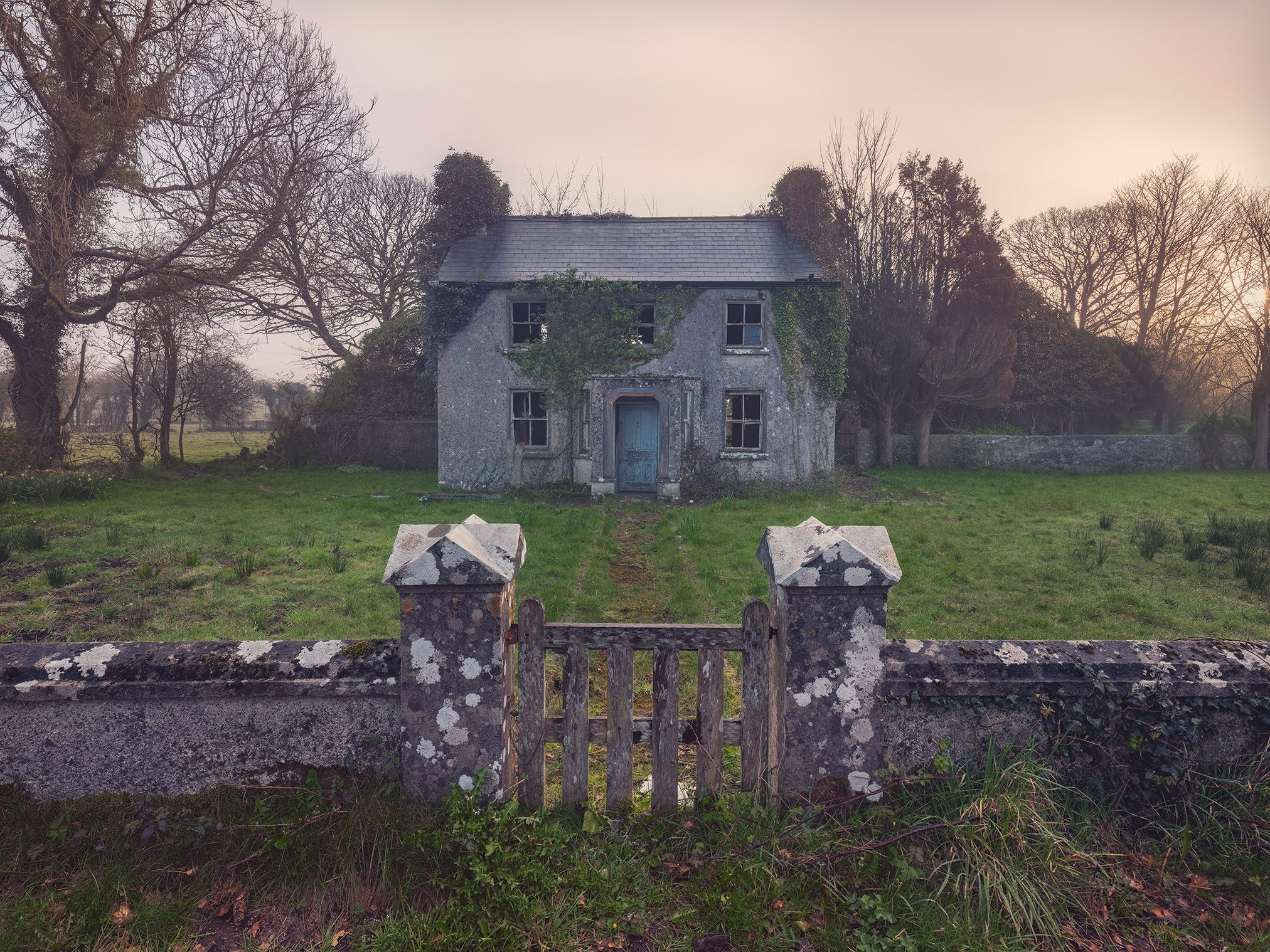 Efeuüberwachsene Ruine am Ende eines Schotterwegs im Morgennebel, Irland