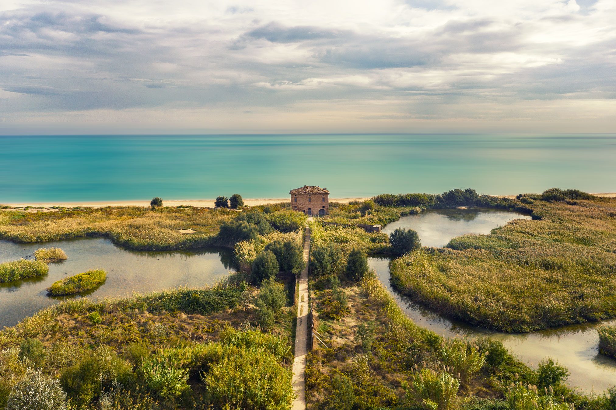 Quadratisches Steinhaus in einer Lagunenlandschaft an der Adriaküste, Italien