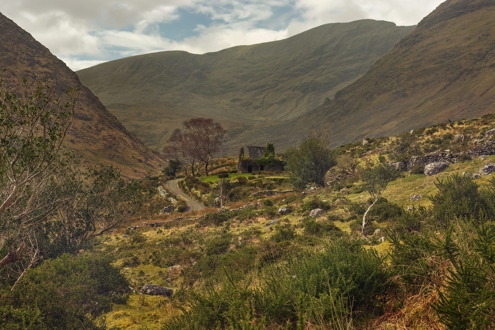 Verfallenes Haus in einem weiten Bergtal aus der Distanz, Irland