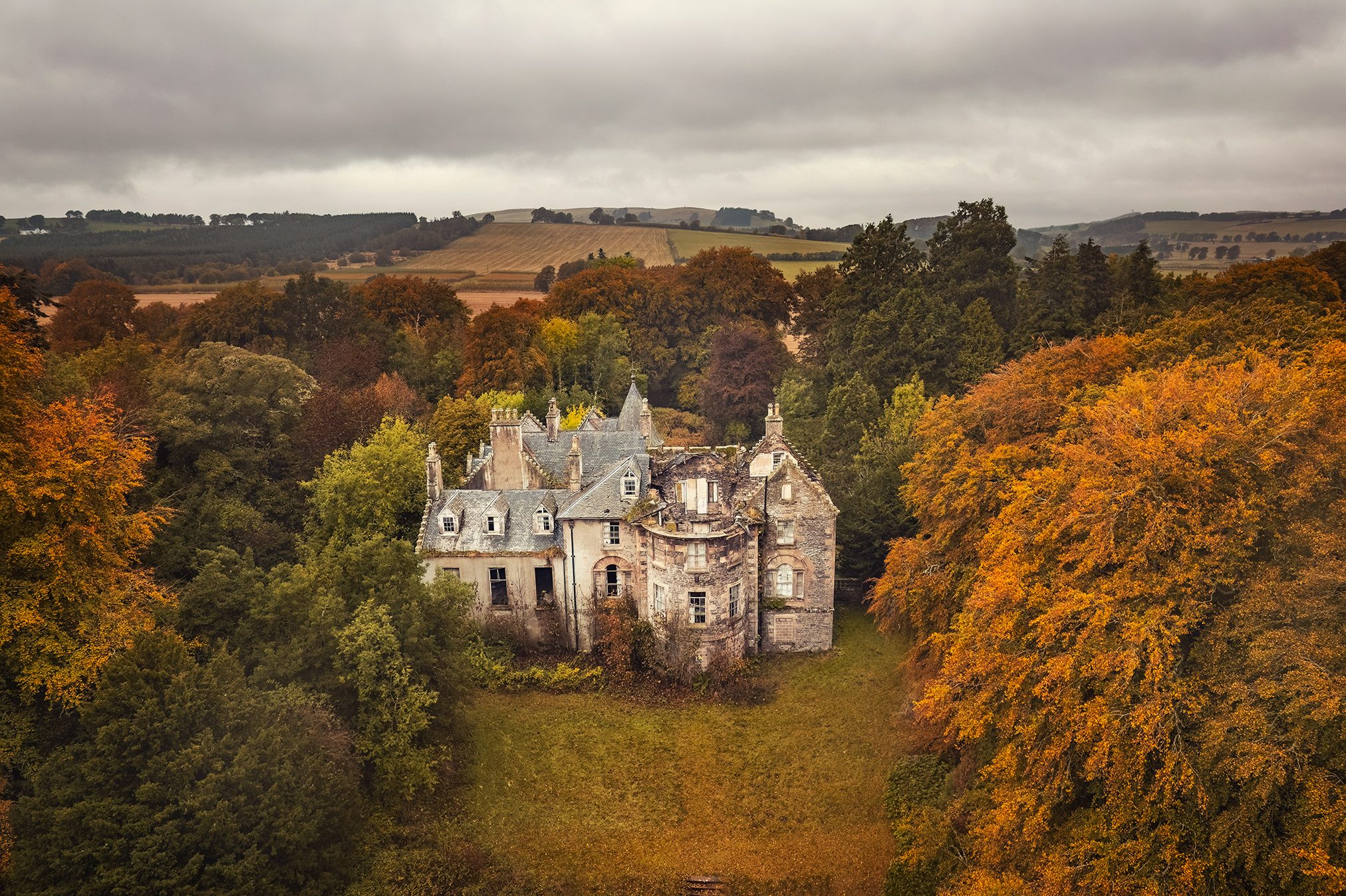 Herrschaftshaus mit Türmchen inmitten herbstlich gefärbter Bäume, Schottland