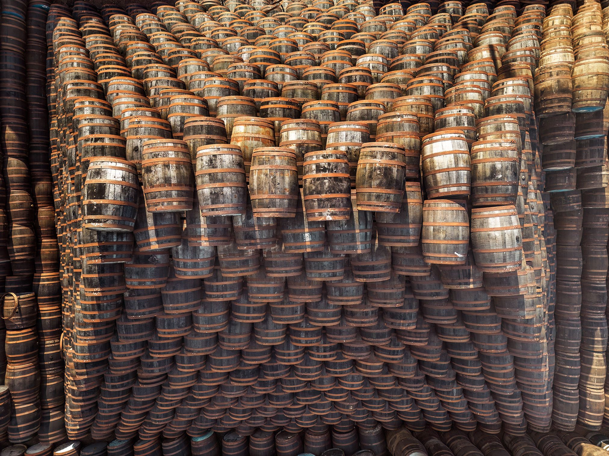 Densely stacked wooden barrels at a whisky distillery in Scotland