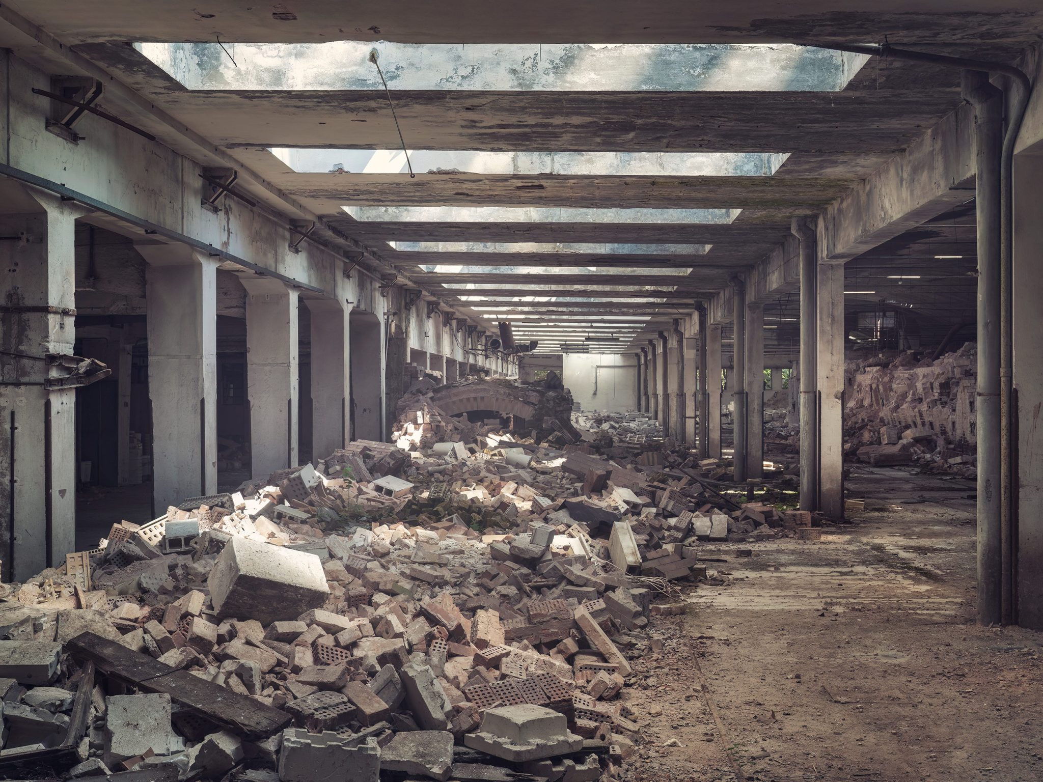 Piles of rubble in a long corridor of a former ceramics factory in Italy
