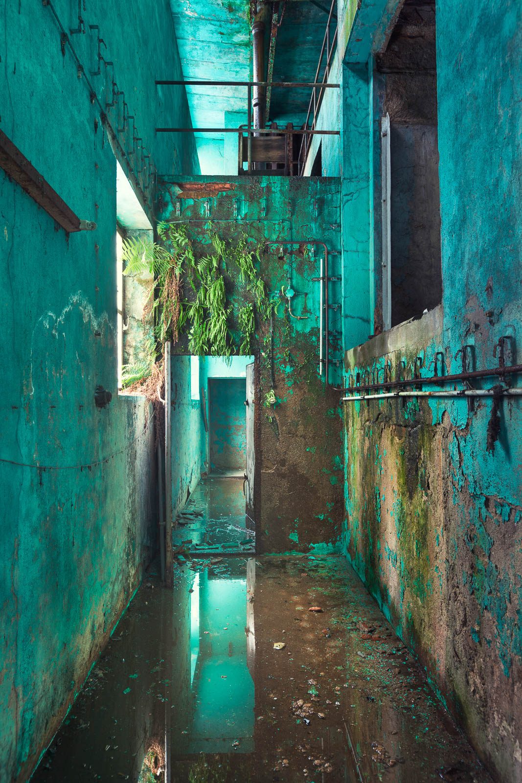 Turquoise corridor with peeling paint in a former paper factory in Germany