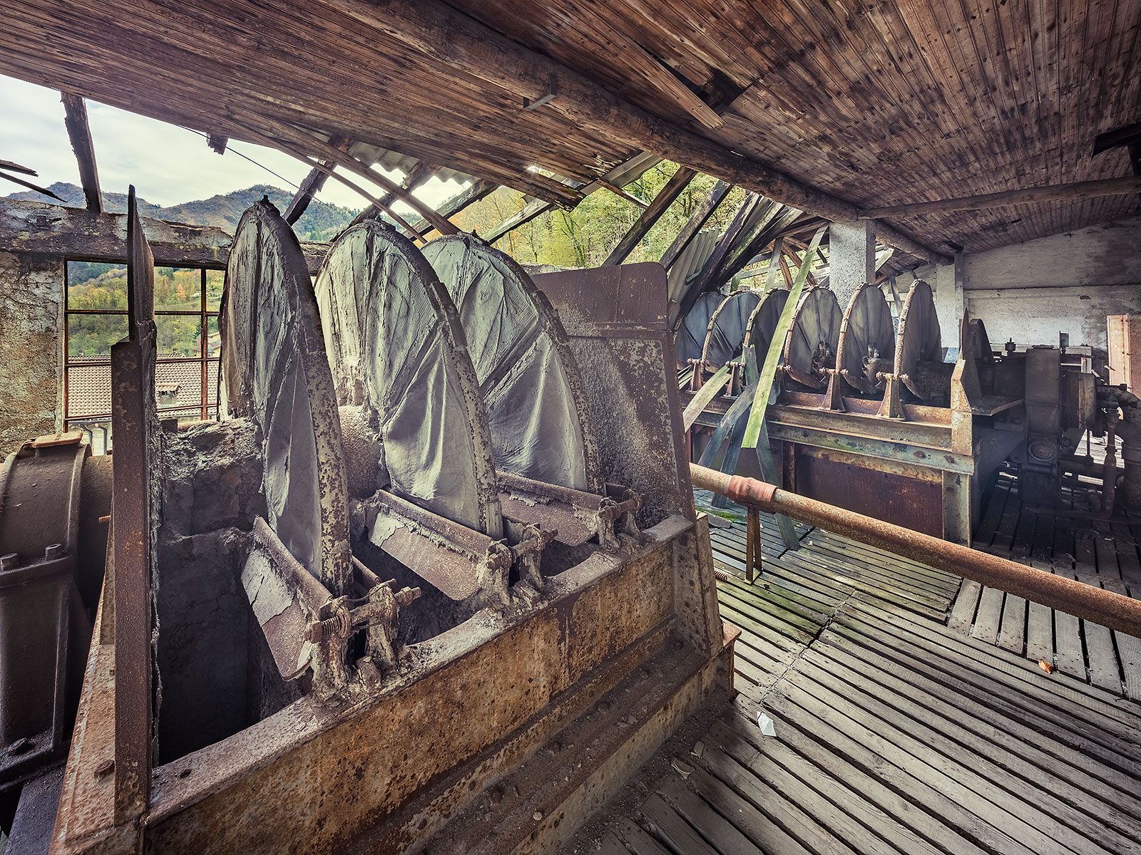 Round screening drums beneath a wooden roof in a factory at the edge of the Alps in Italy