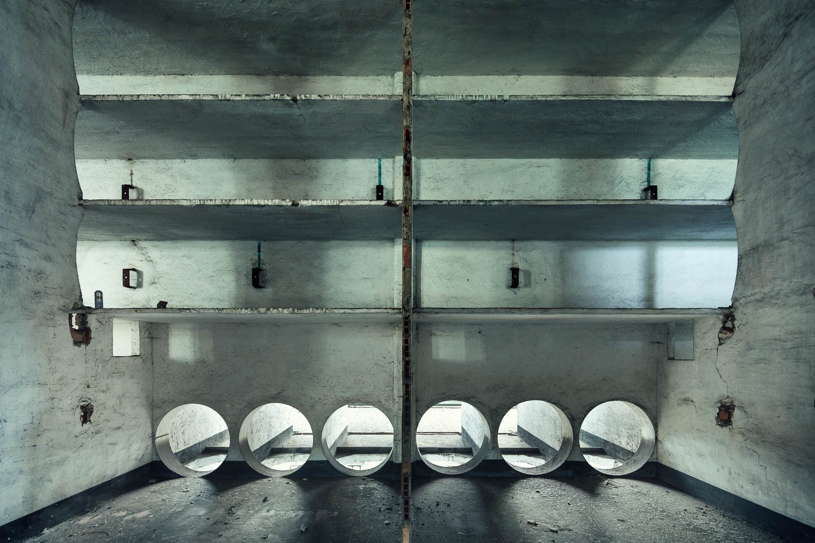 Symmetrischer Betontunnel mit runden Öffnungen in einem vergessenen Kraftwerk in Italien