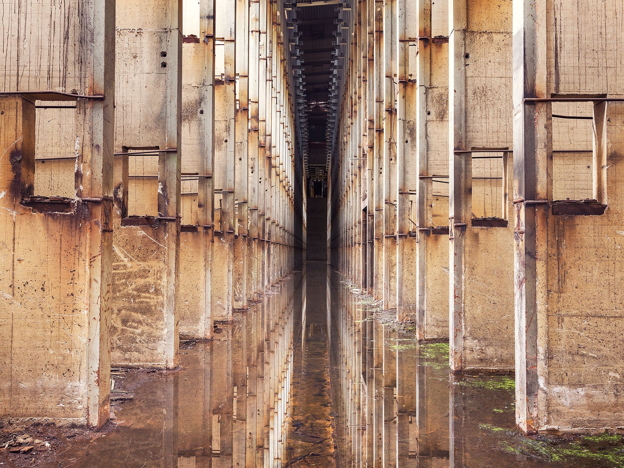 Flooded hall with rusted steel brackets in an industrial ruin in Belgium