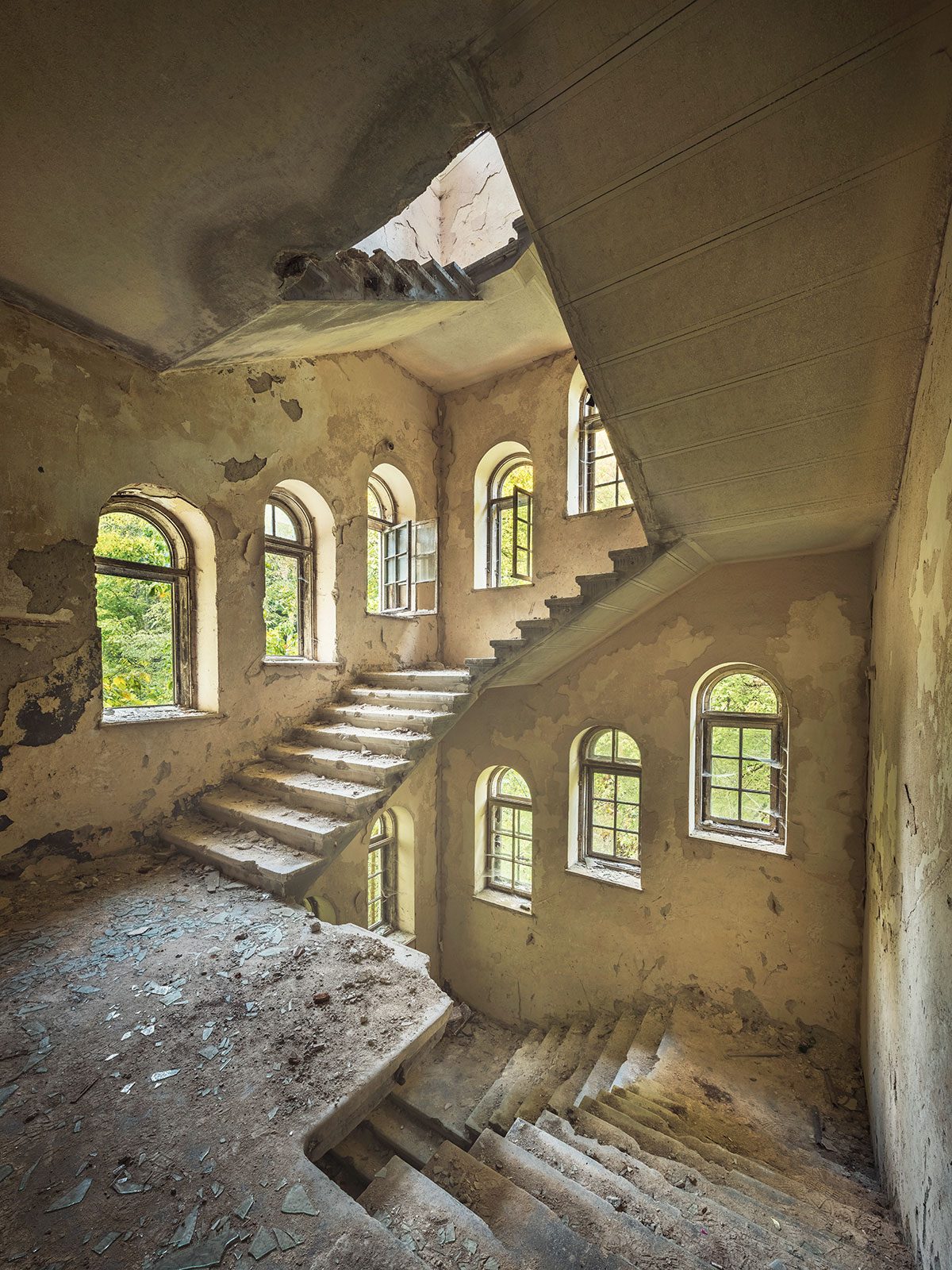 Treppenhaus mit zahlreichen Rundbogenfenstern in einem verlassenen Sanatorium in Rumänien