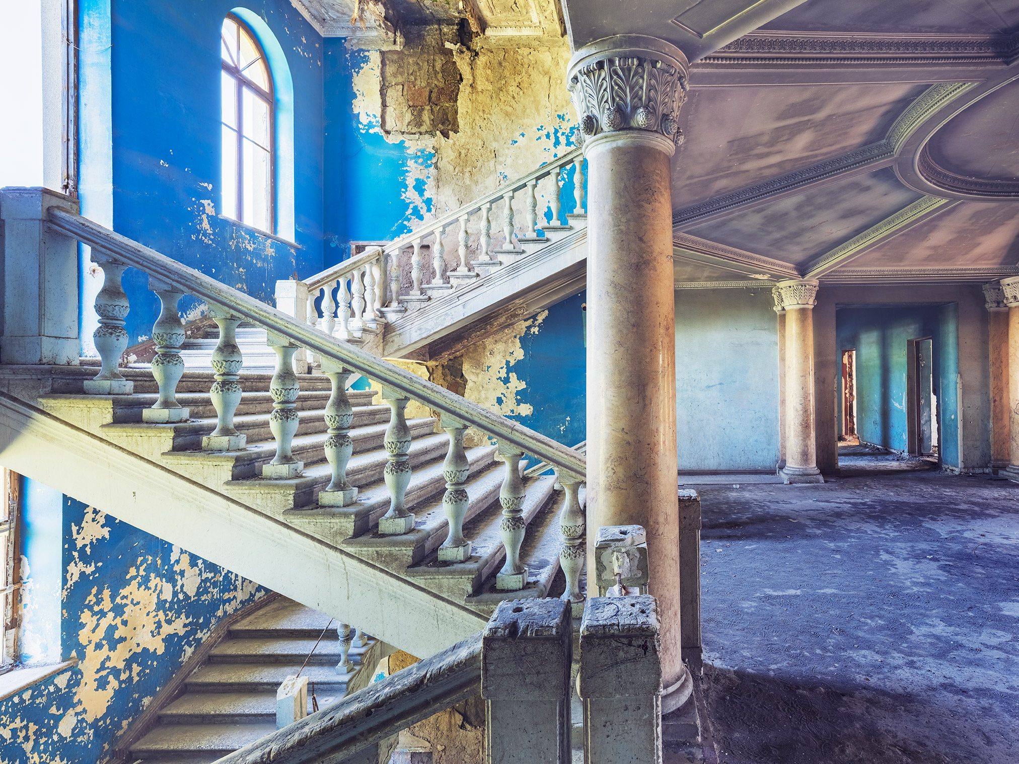 Blue painted staircase with a marble column in an abandoned hotel in Georgia