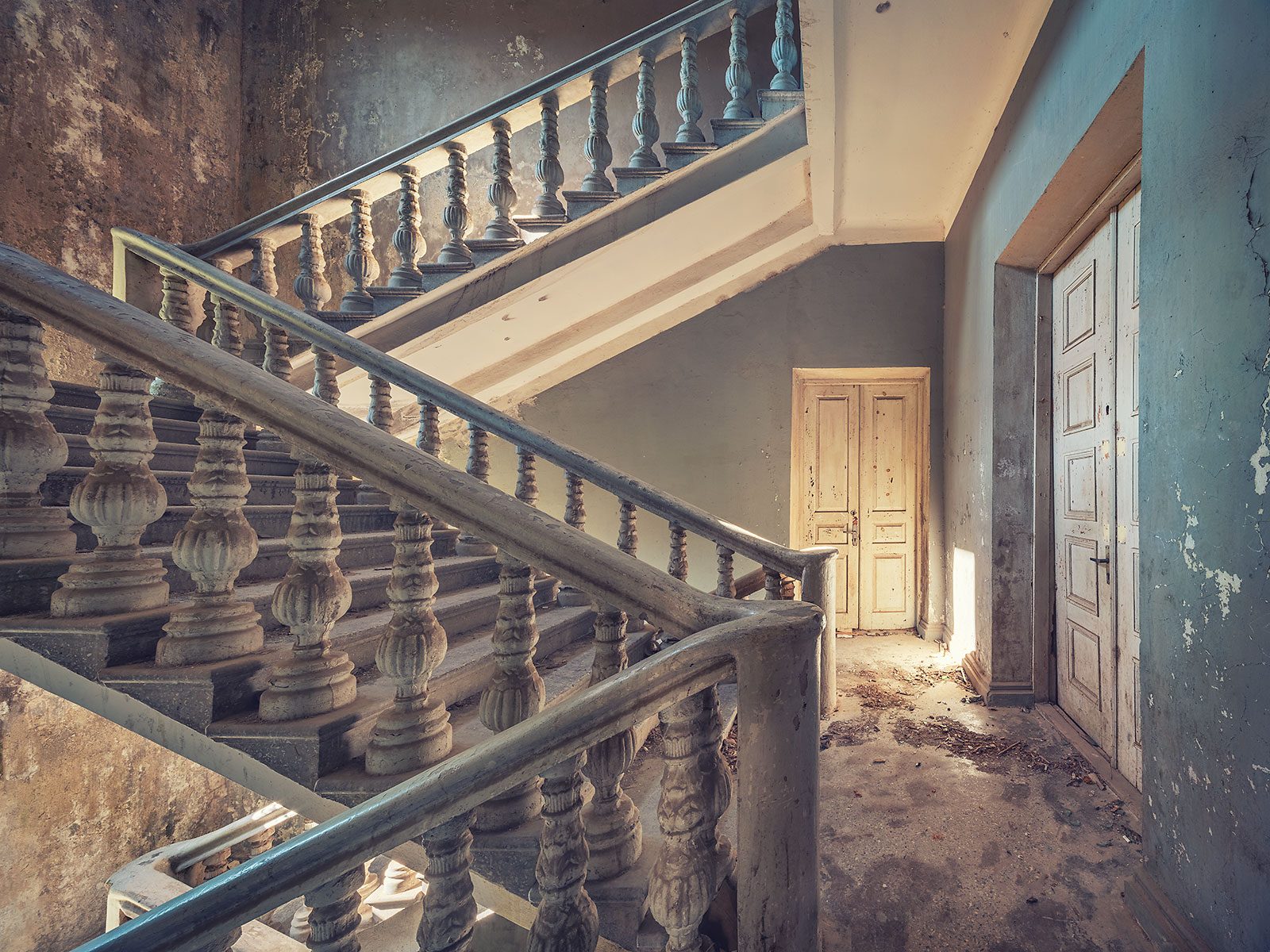 Treppenhaus mit gedrechselter Balustrade und blaugrünen Wänden in einem vergessenen Kulturhaus in Georgien