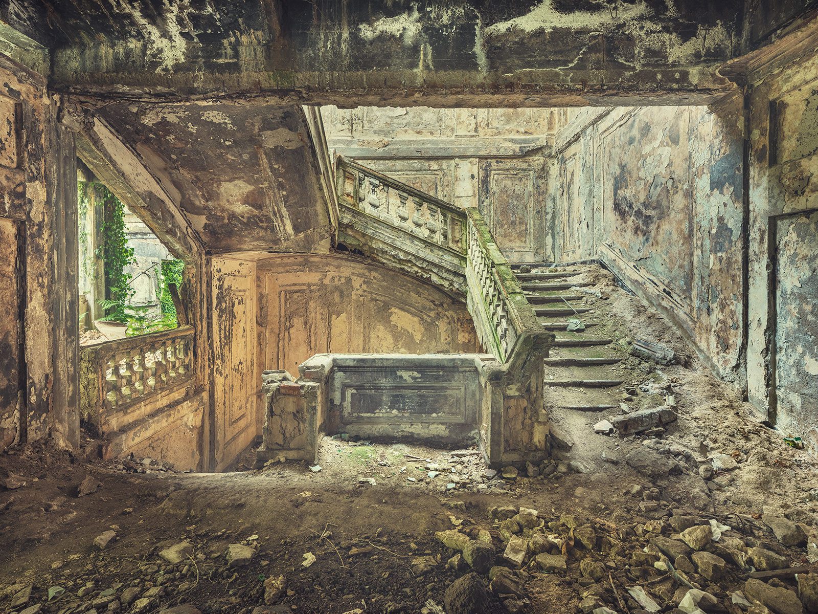 Treppenhaus mit Ausblick auf Efeu durch ein Fenster in einem verlassenen Regierungsgebäude in Georgien
