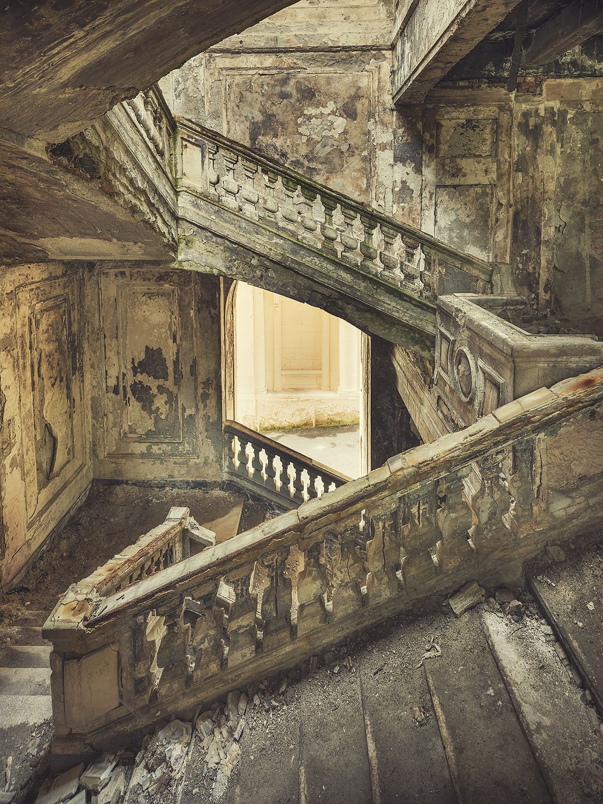 Balustraded staircase with a view toward a bright doorway in an abandoned government building in Georgia
