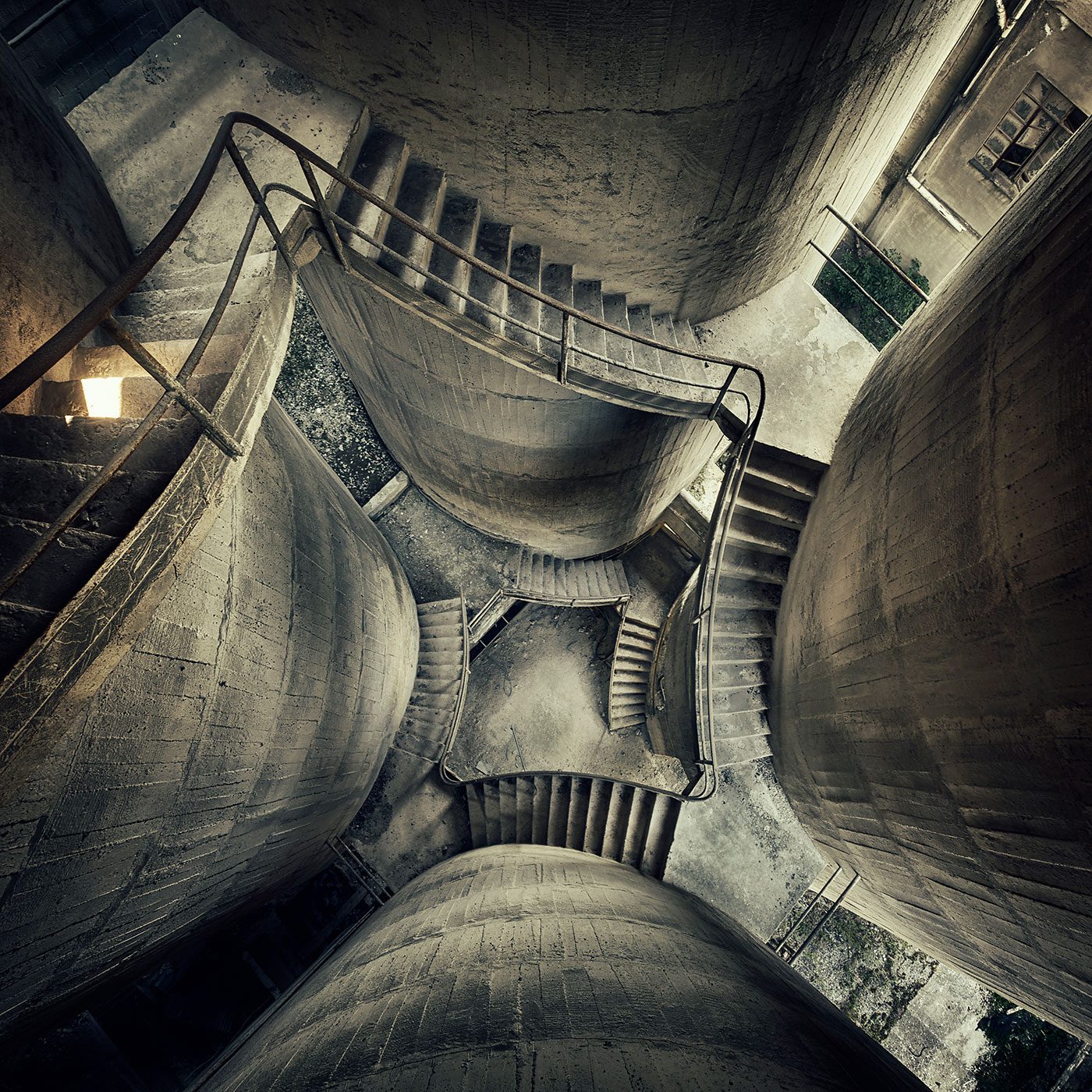 View down into abandoned concrete silos with spiralling staircases in an old factory in Italy
