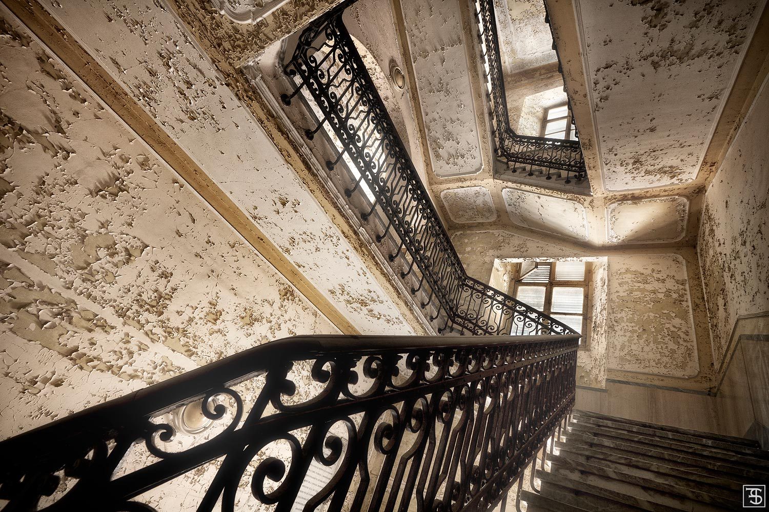 Staircase with heavily flaking plaster in an abandoned psychiatric institution in Italy
