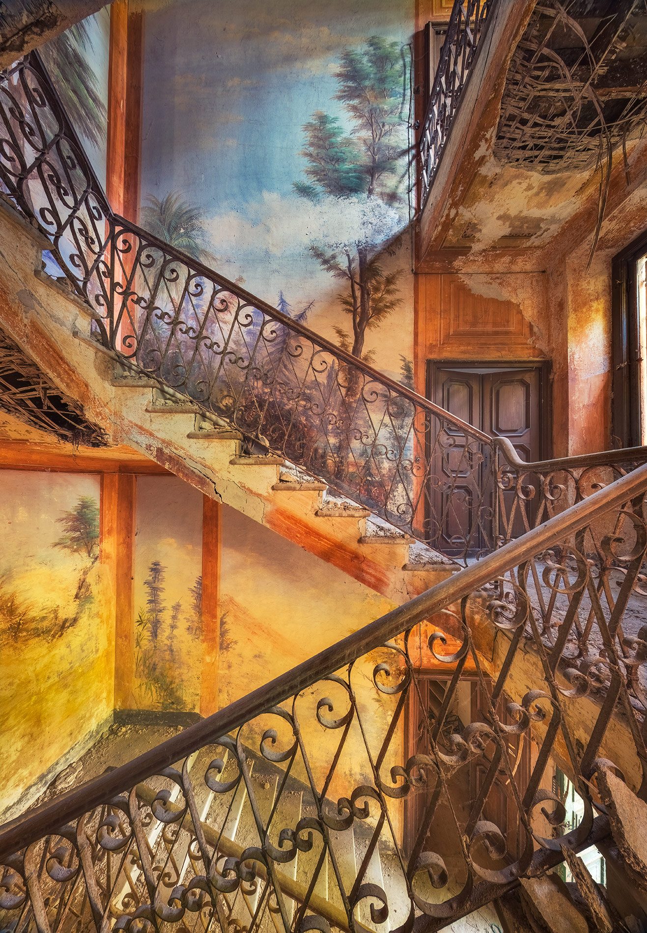 Treppenhaus mit gemalter Waldlandschaft an den Wänden in einer verlassenen Villa in Italien