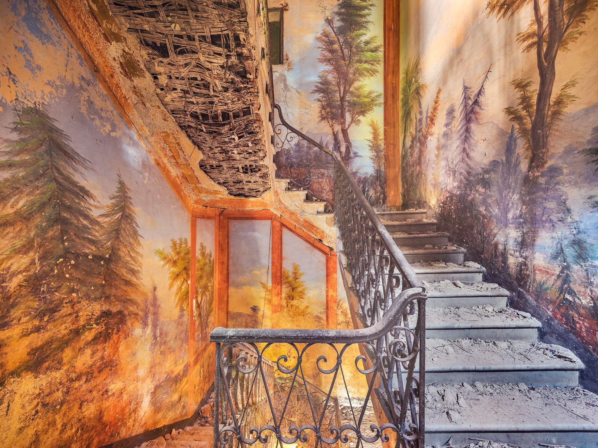 Staircase beneath a painted forest landscape in an abandoned villa in Italy
