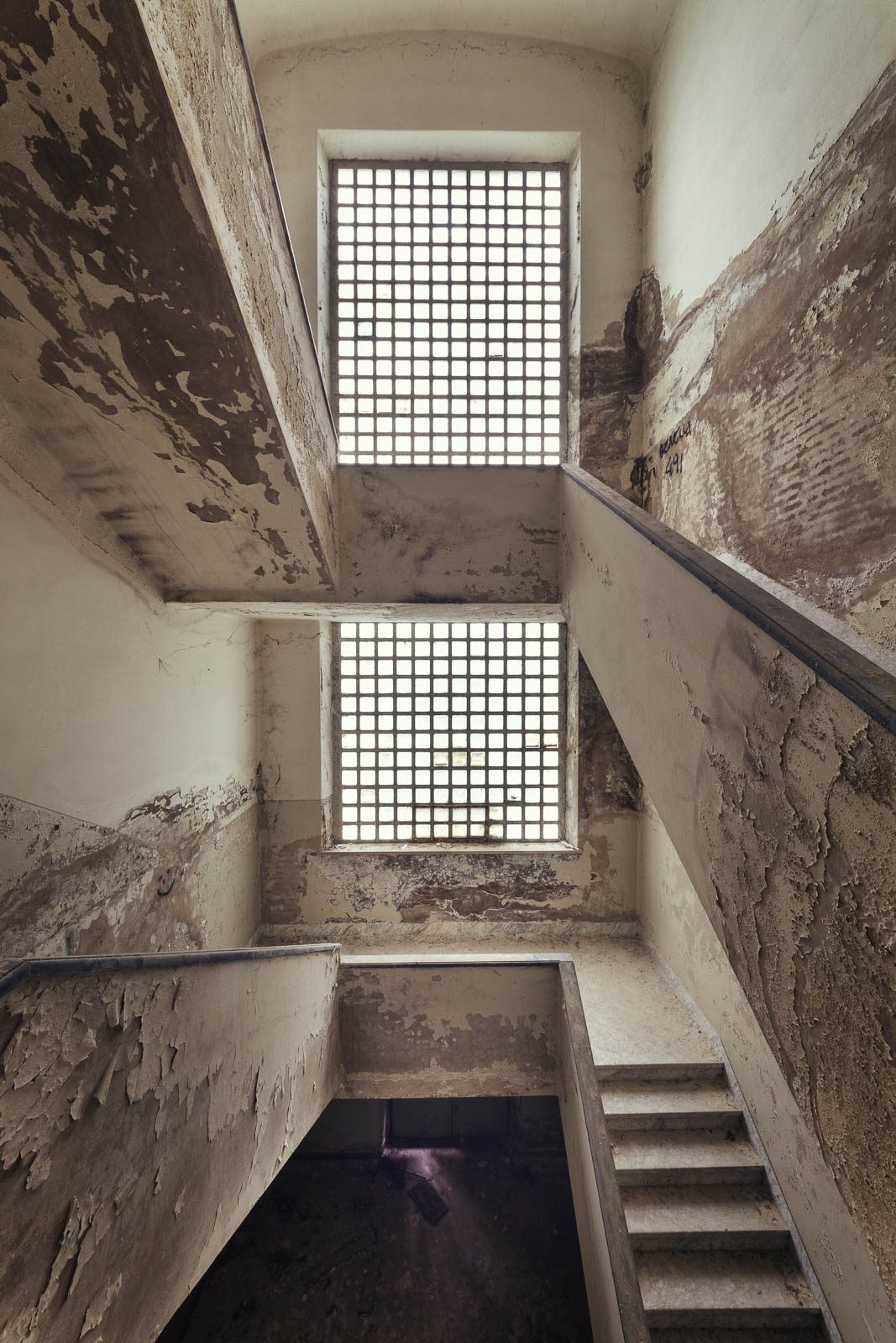 Blick nach oben in ein Treppenhaus mit Gitterfenstern in einem brutalistischen Krankenhaus in Italien