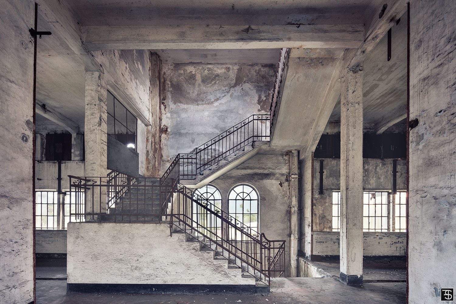 Industrial concrete staircase before arched windows in a decommissioned power plant in Italy