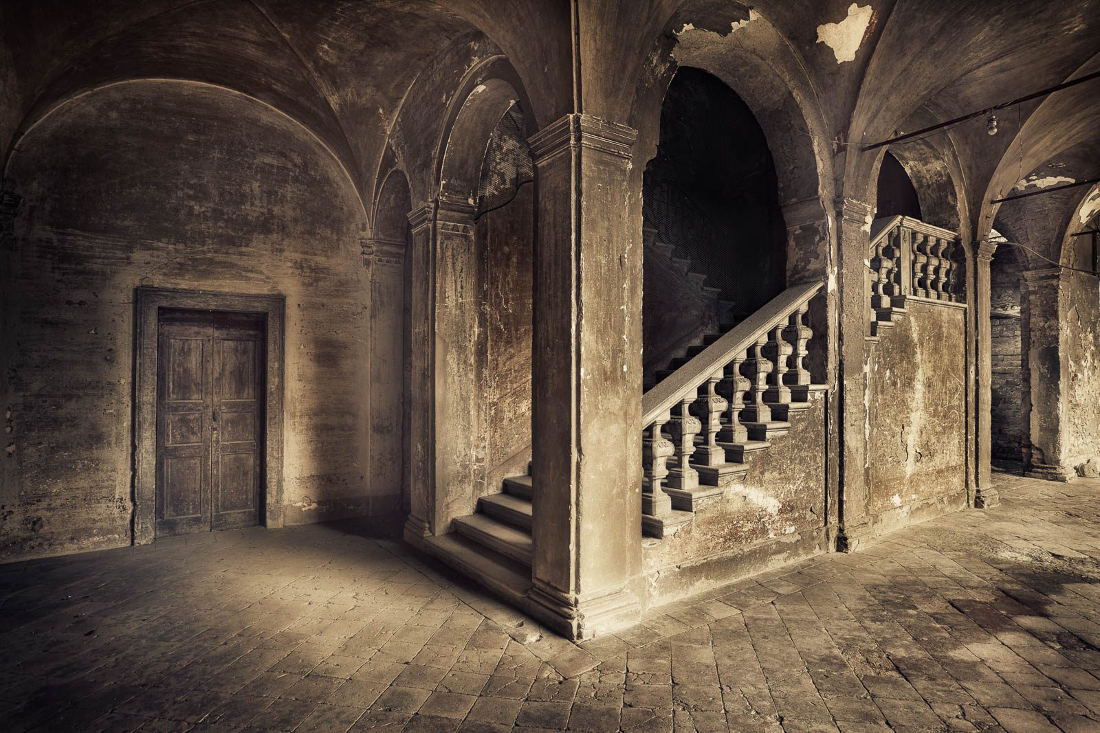 Arcaded corridor with a staircase in an abandoned castle in Italy