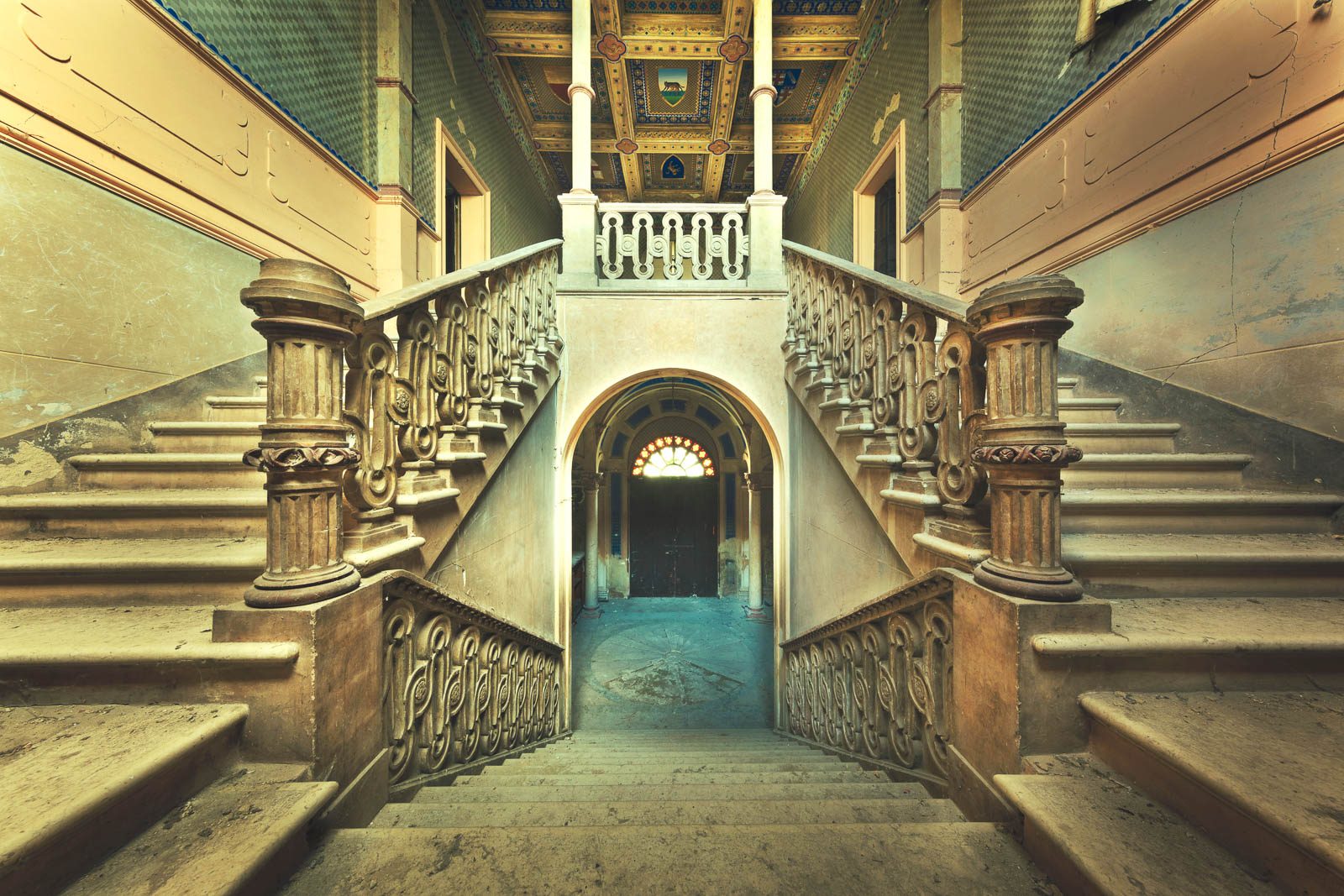 Symmetrische Doppeltreppe unter bemalter Balkendecke in einem beschädigten Castello in Italien