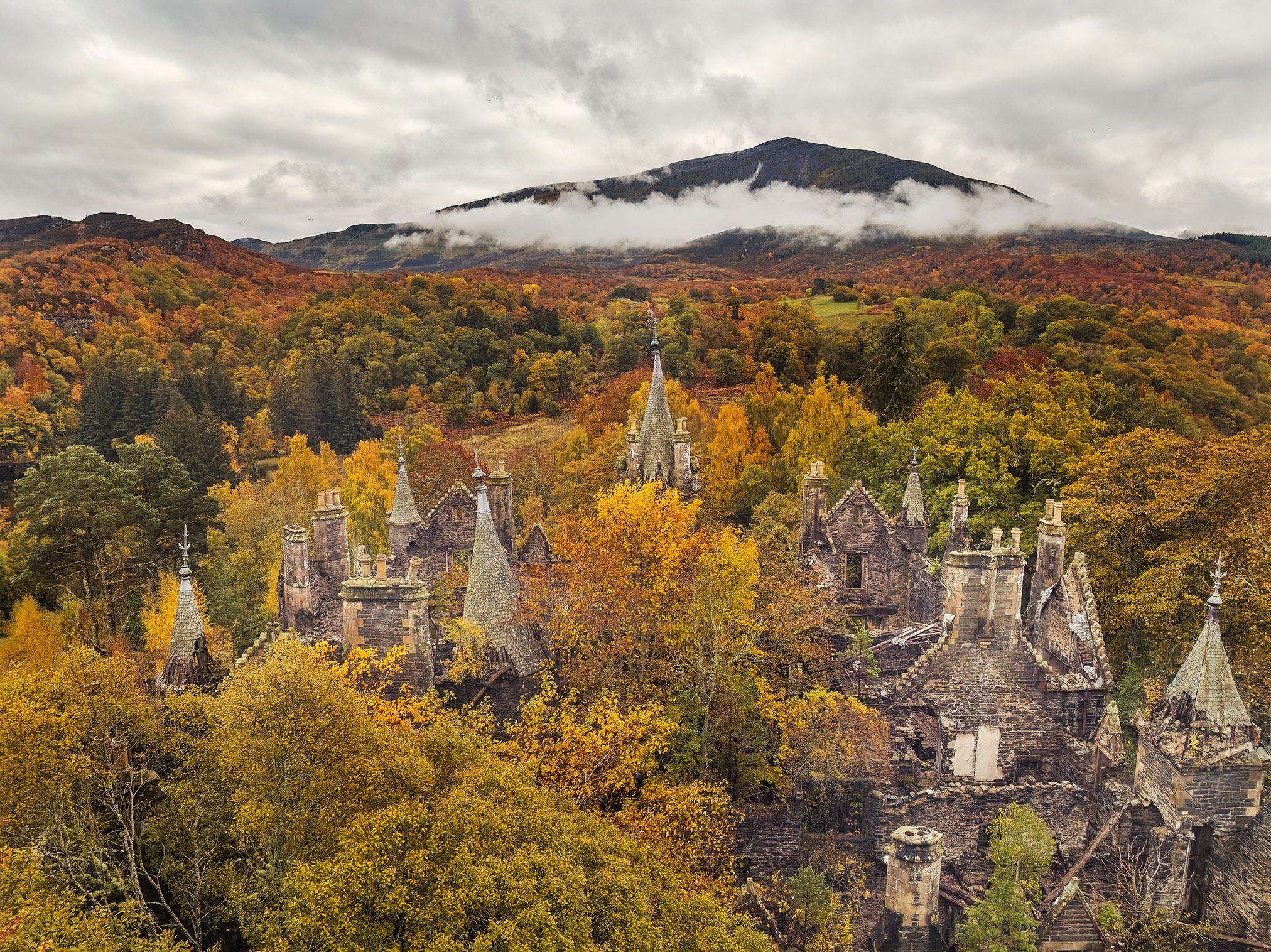 Türme mit Turmspitzen im herbstlichen Wald, Schottland