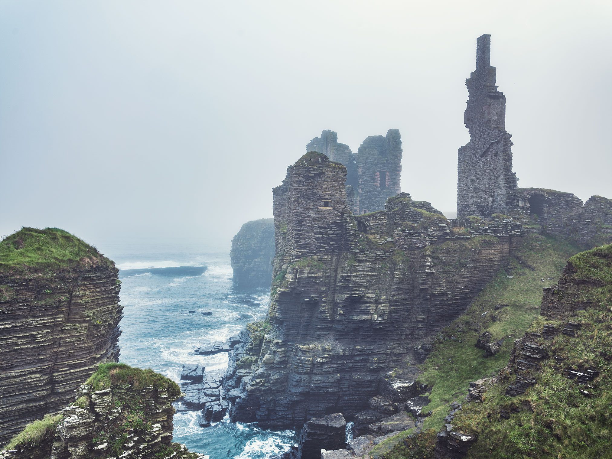 Ruin on a fog covered sea cliff, Scotland