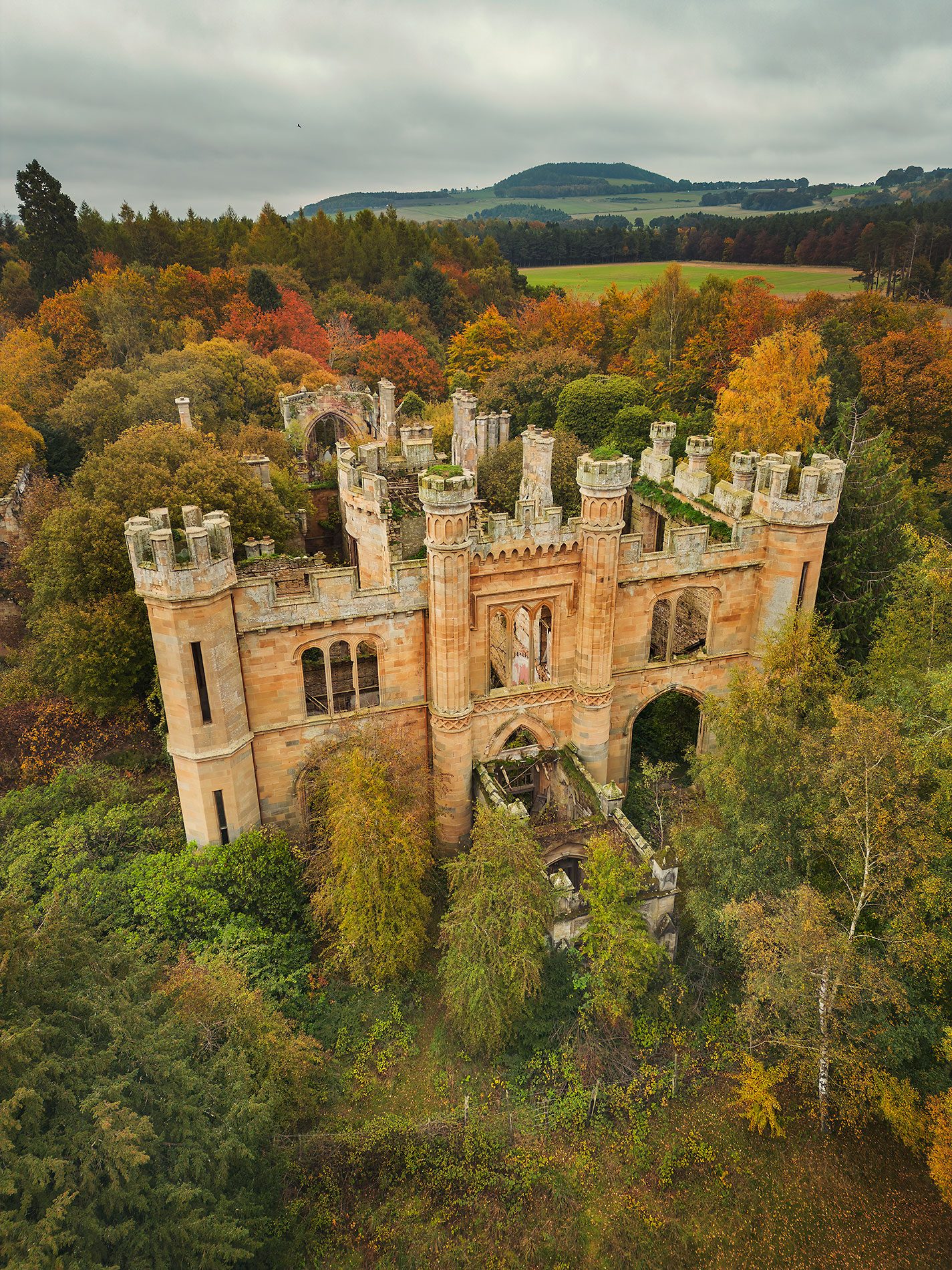 Ornate mansion ruin with towers in an autumn forest, Scotland