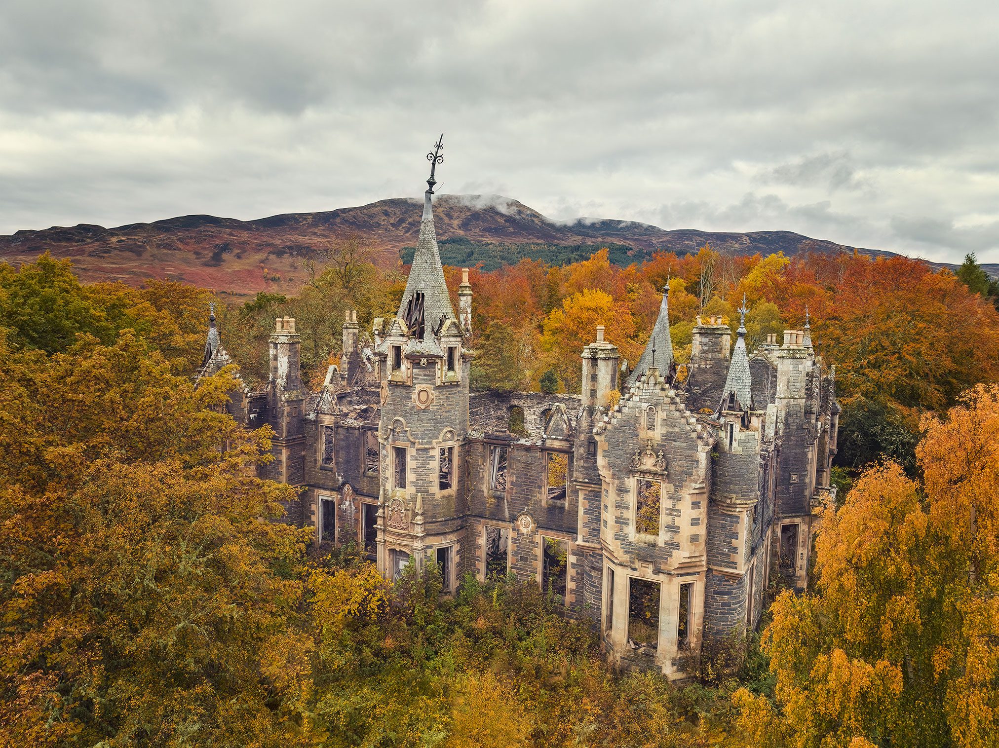 Castle ruin with a tower and battlements in an autumn forest, Scotland