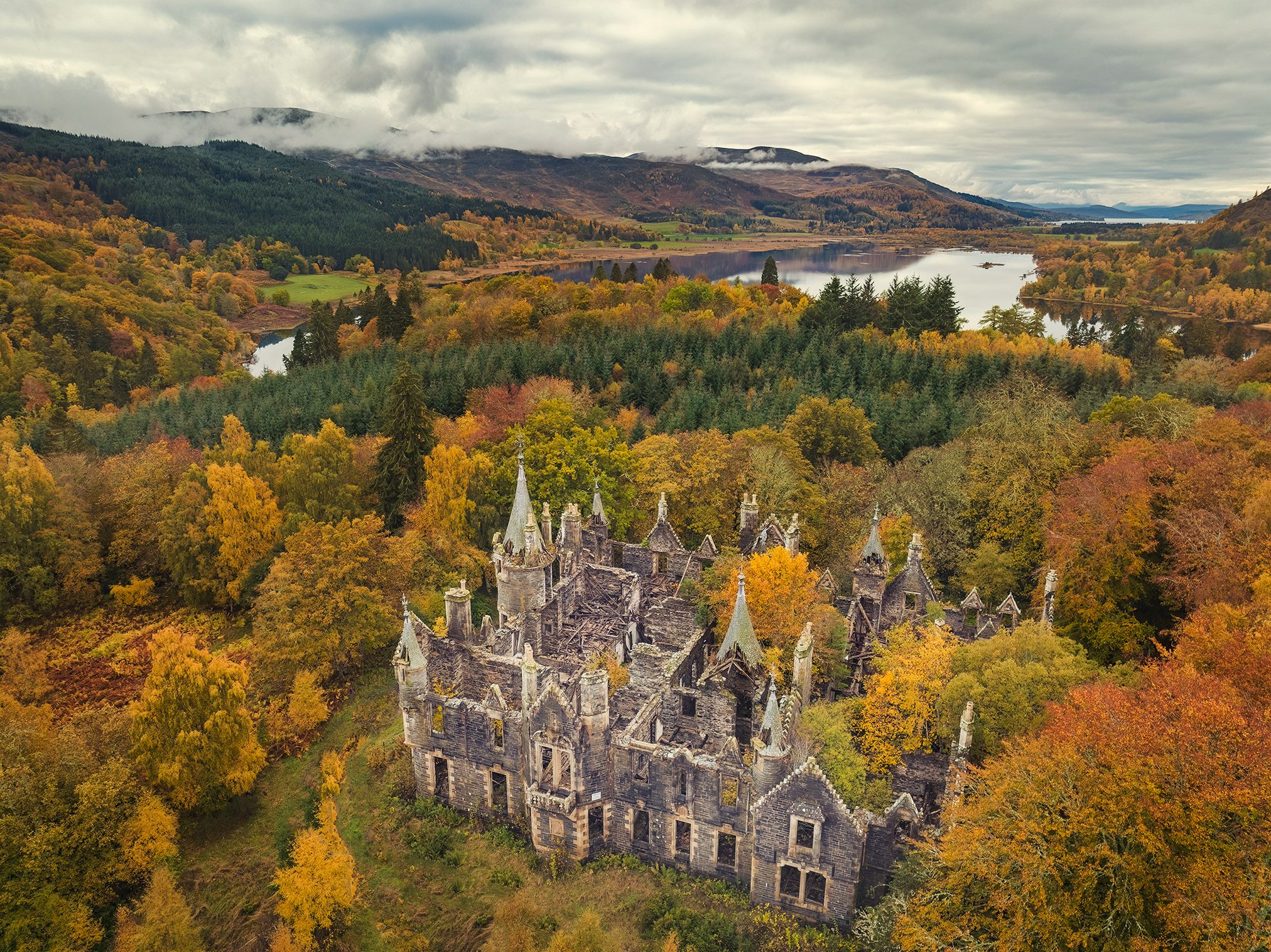 Extensive castle ruin with spired towers in an autumn forest, Scotland