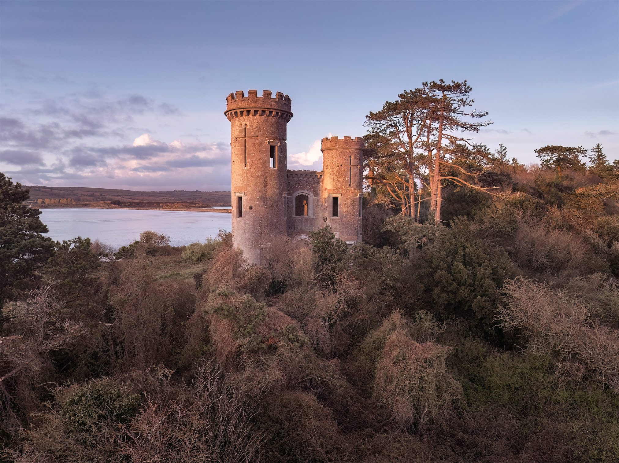 Round tower folly by the water in evening light, Ireland