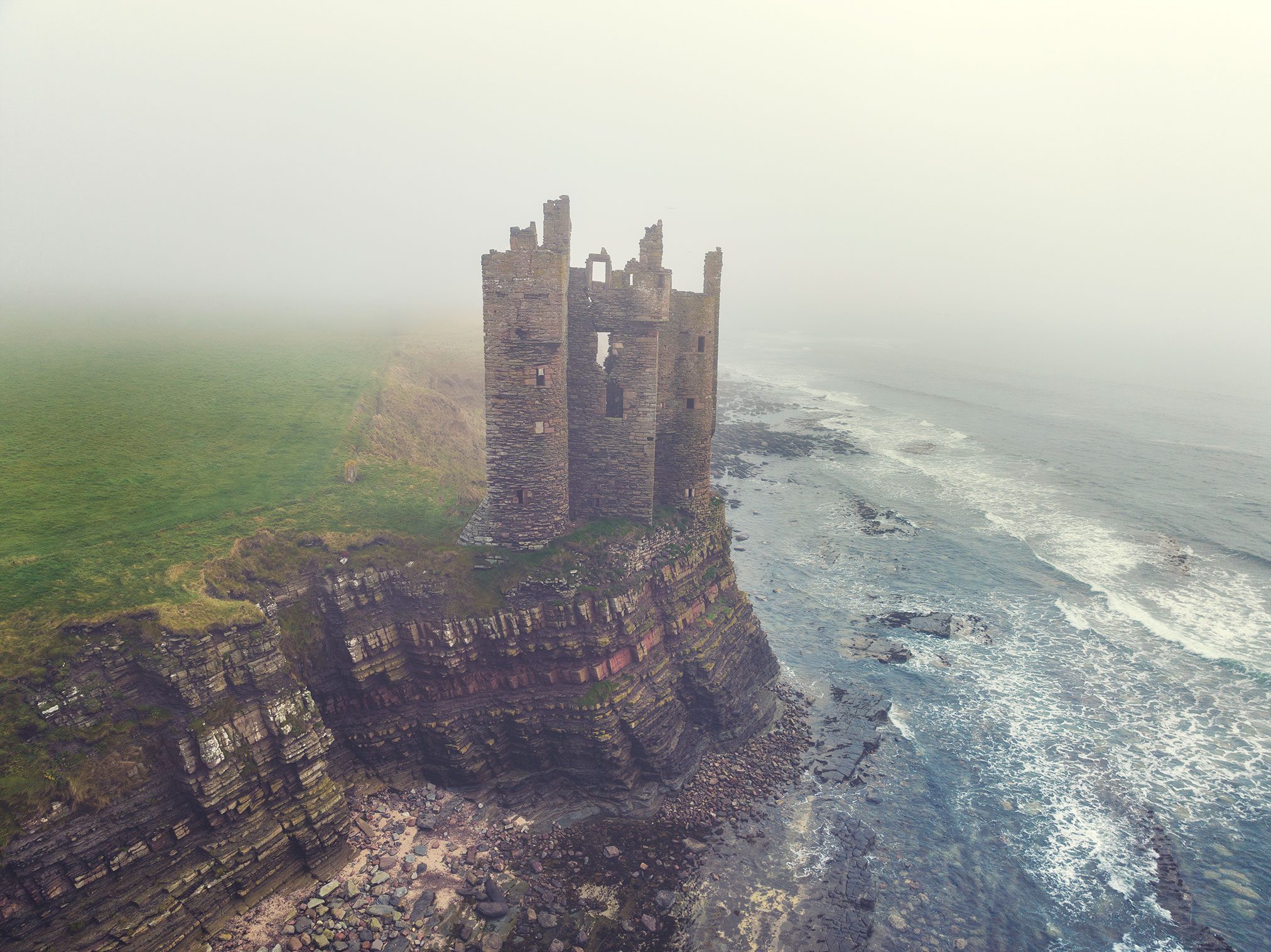Narrow tower ruin in fog on the coast, Scotland