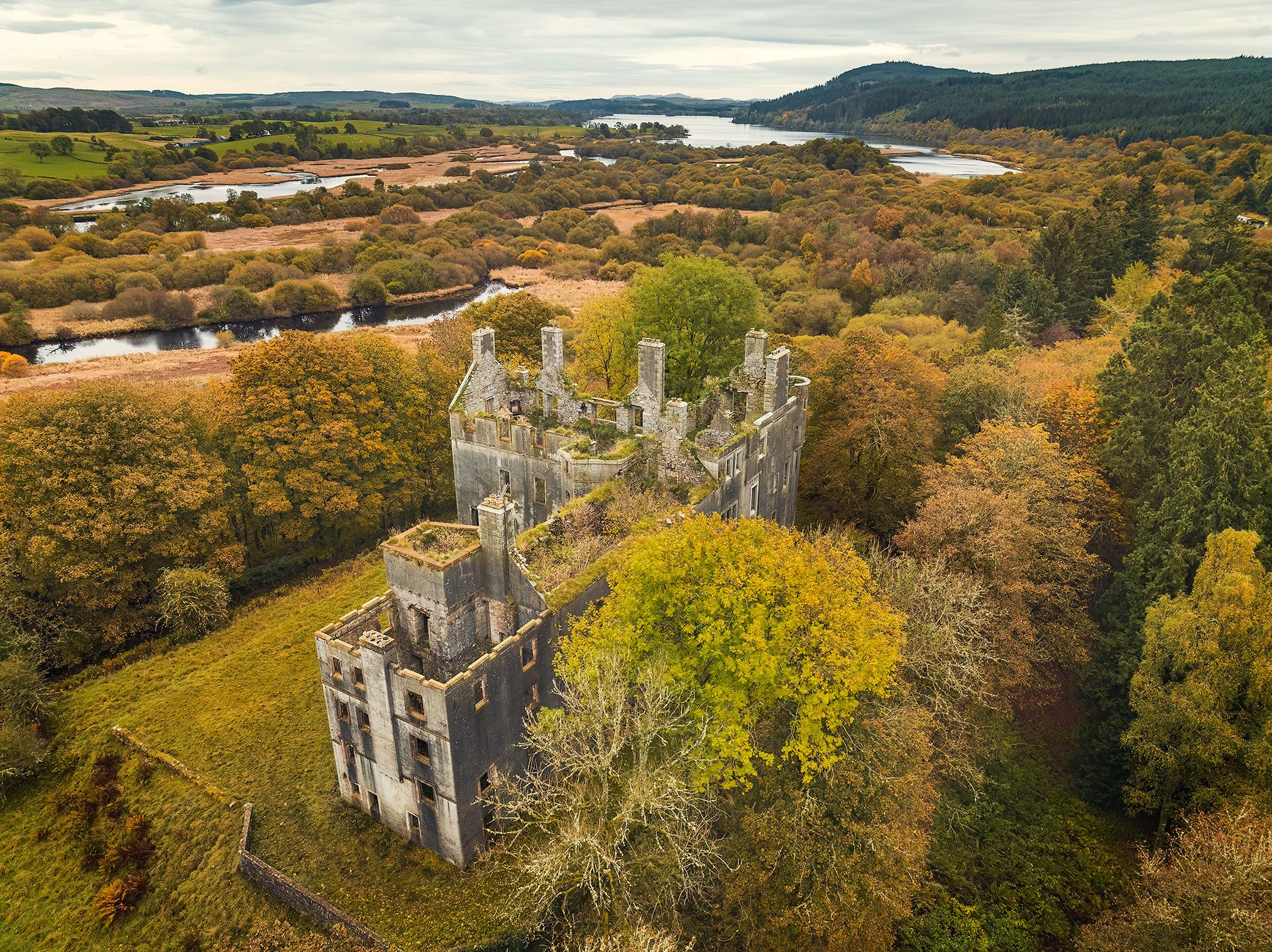 Long castle ruin with rows of chimneys in an autumn forest, Scotland