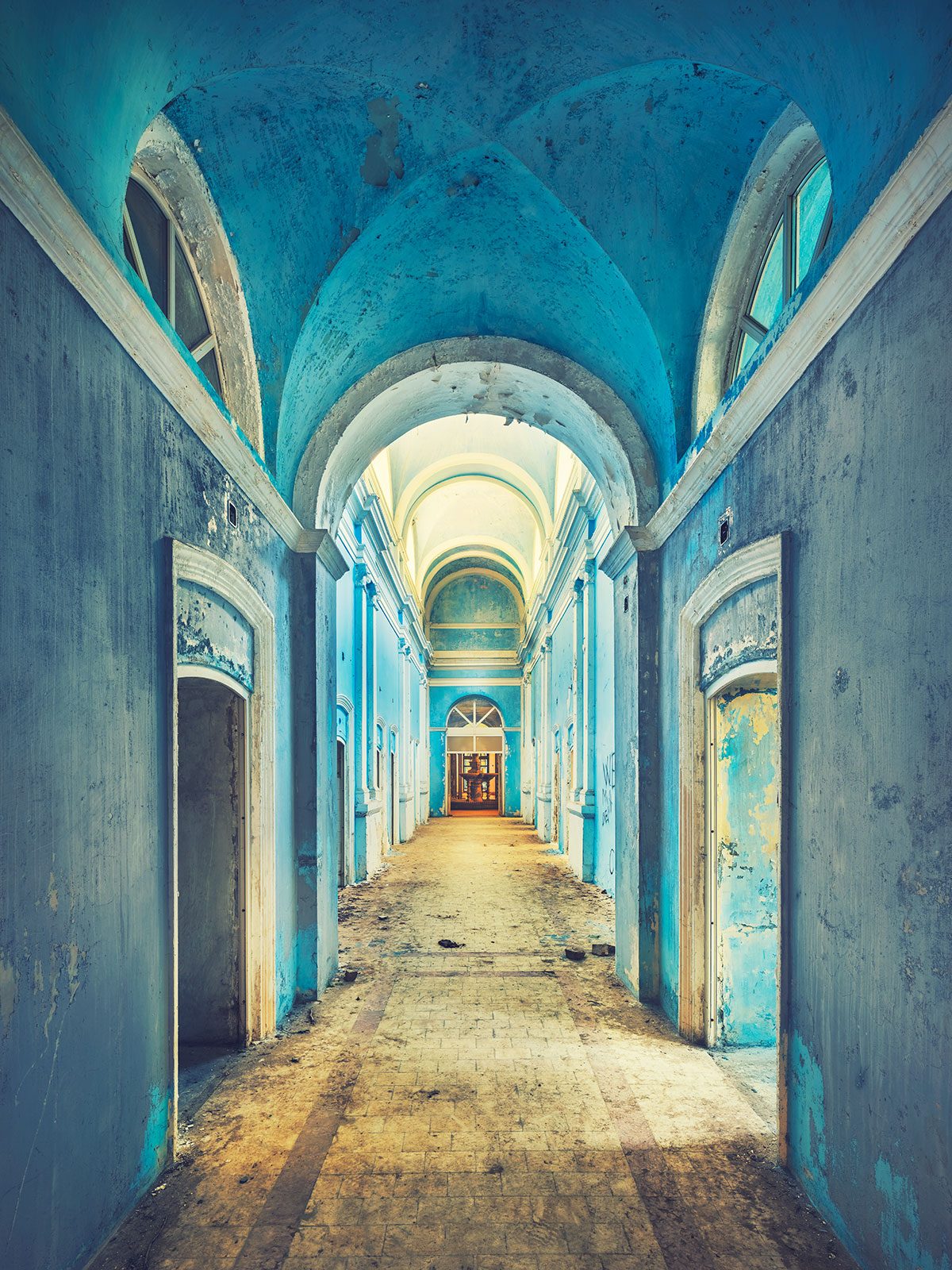 Blue-painted vaulted corridor with doors in a historic bathhouse in Romania