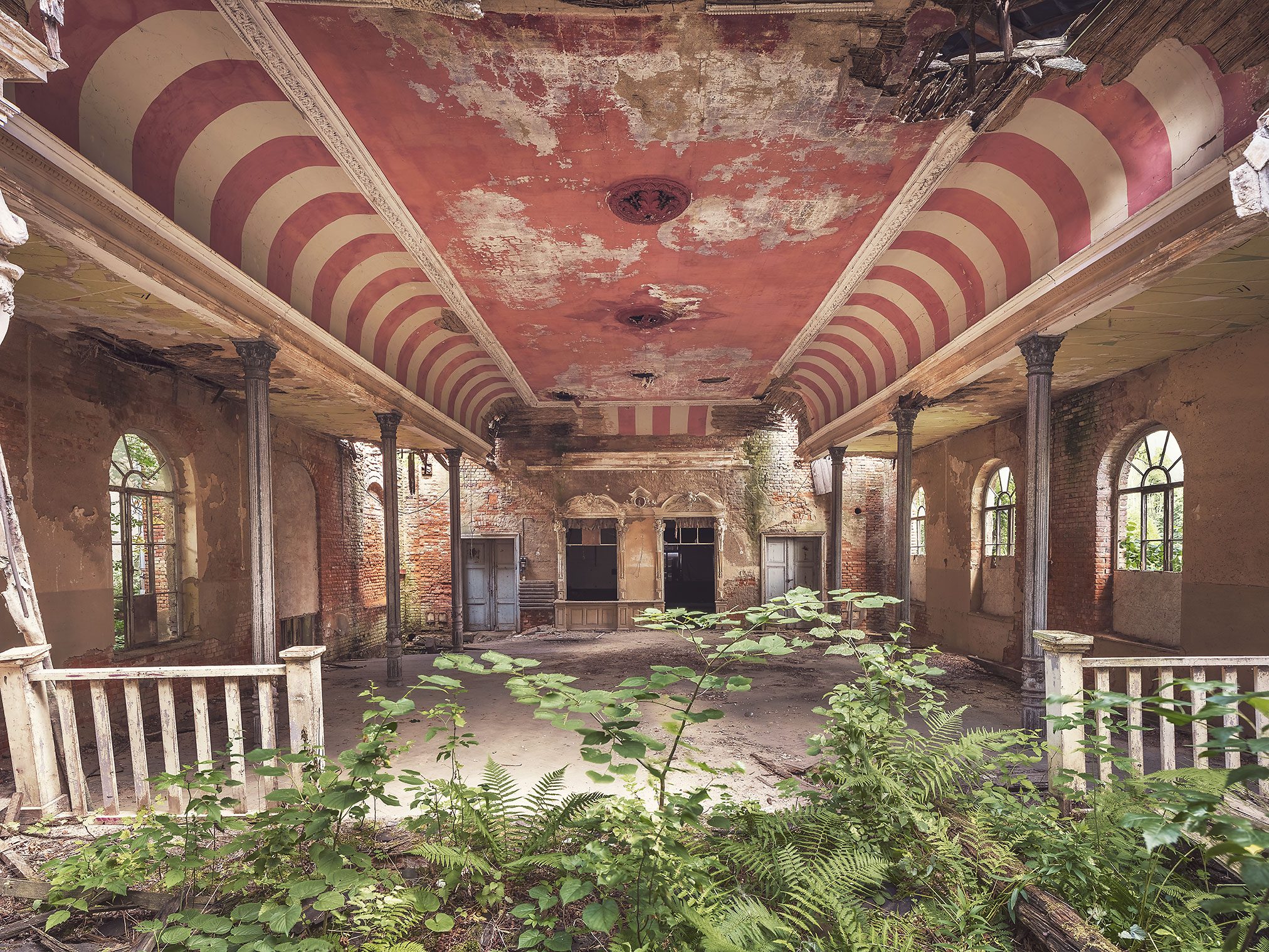 Decaying hall with a red and white striped ceiling canopy and arched windows in Germany