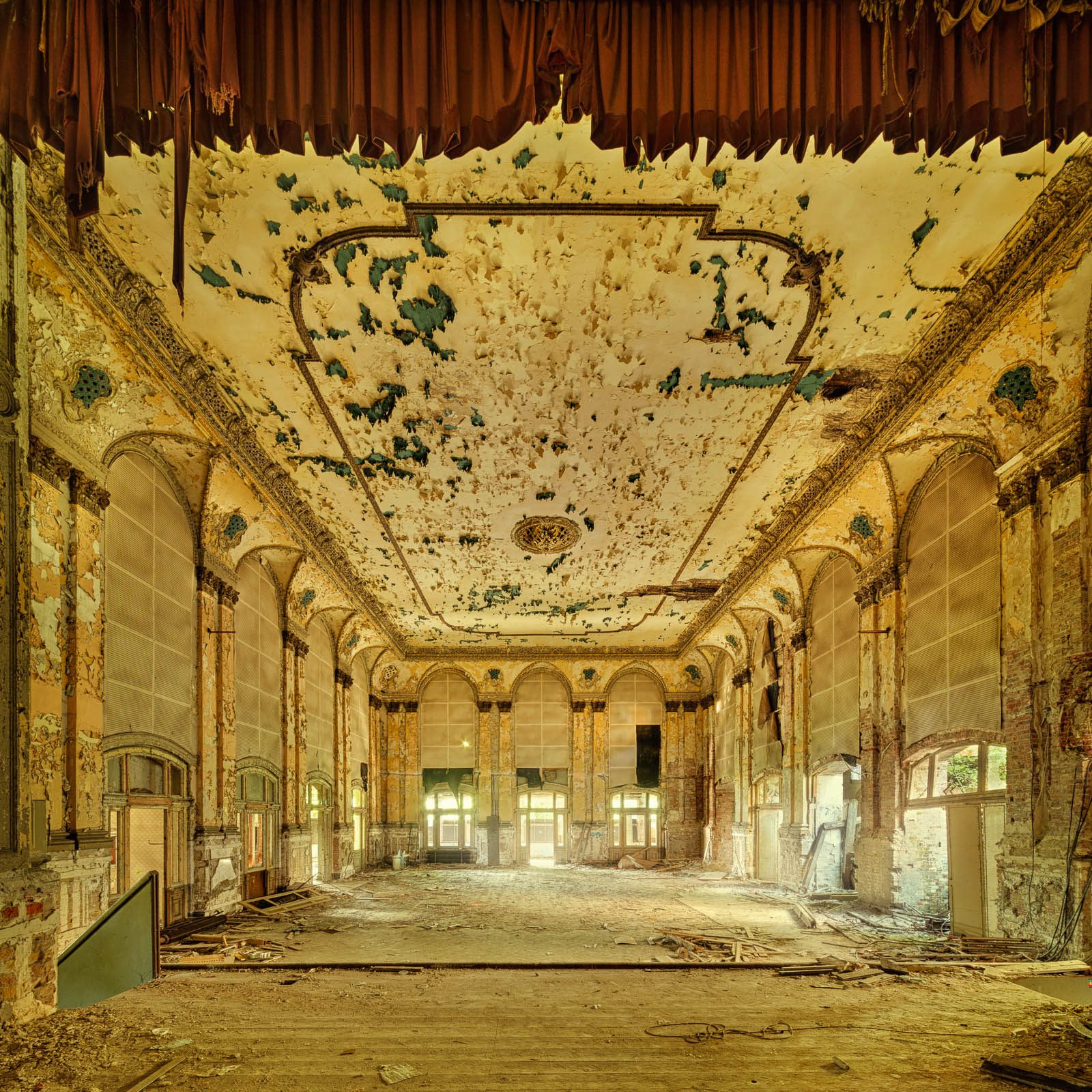 Decaying ballroom with remnants of a curtain and a peeling ceiling in Berlin