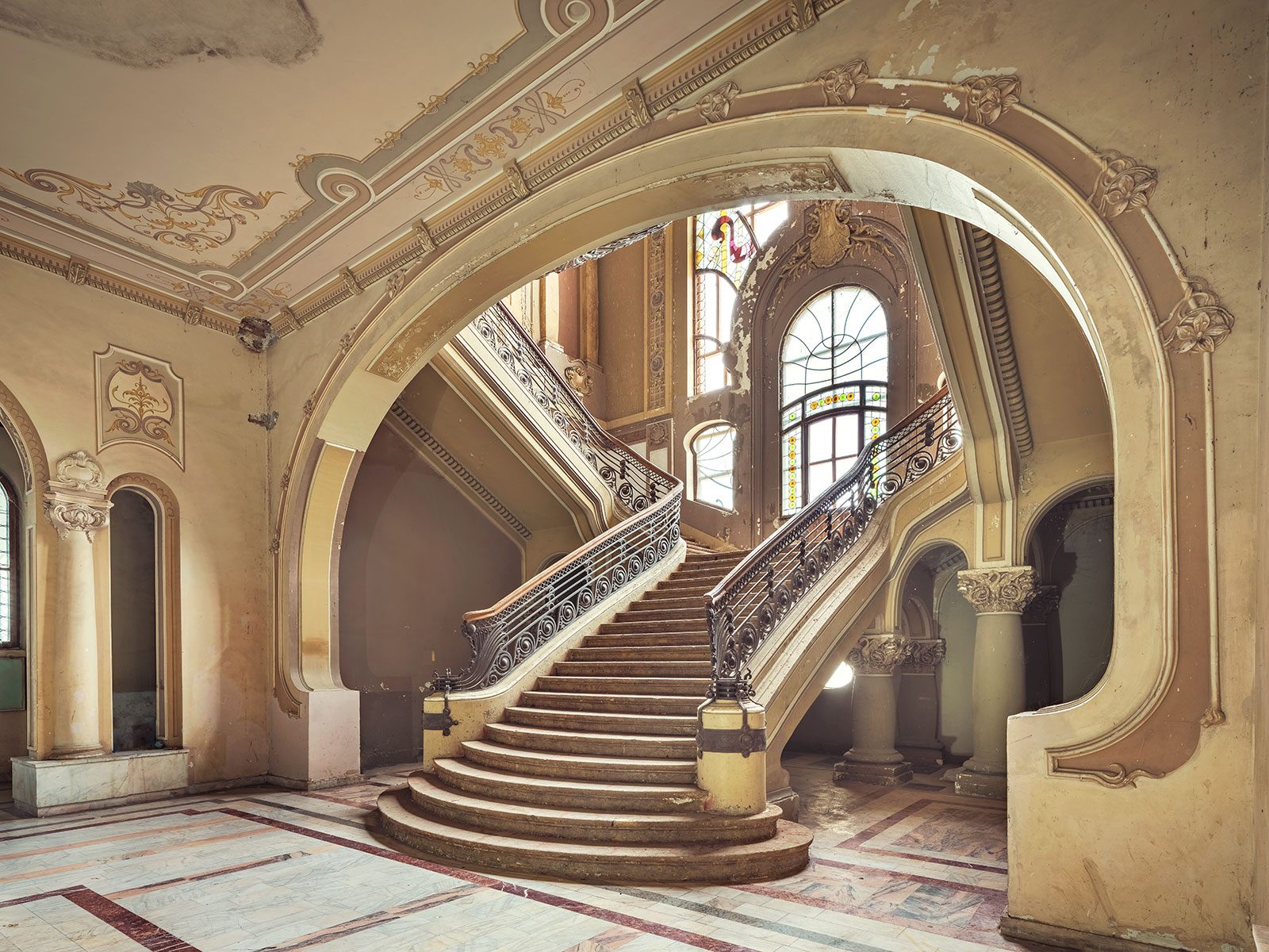 Marble staircase with a wrought-iron railing in a decaying casino in Romania