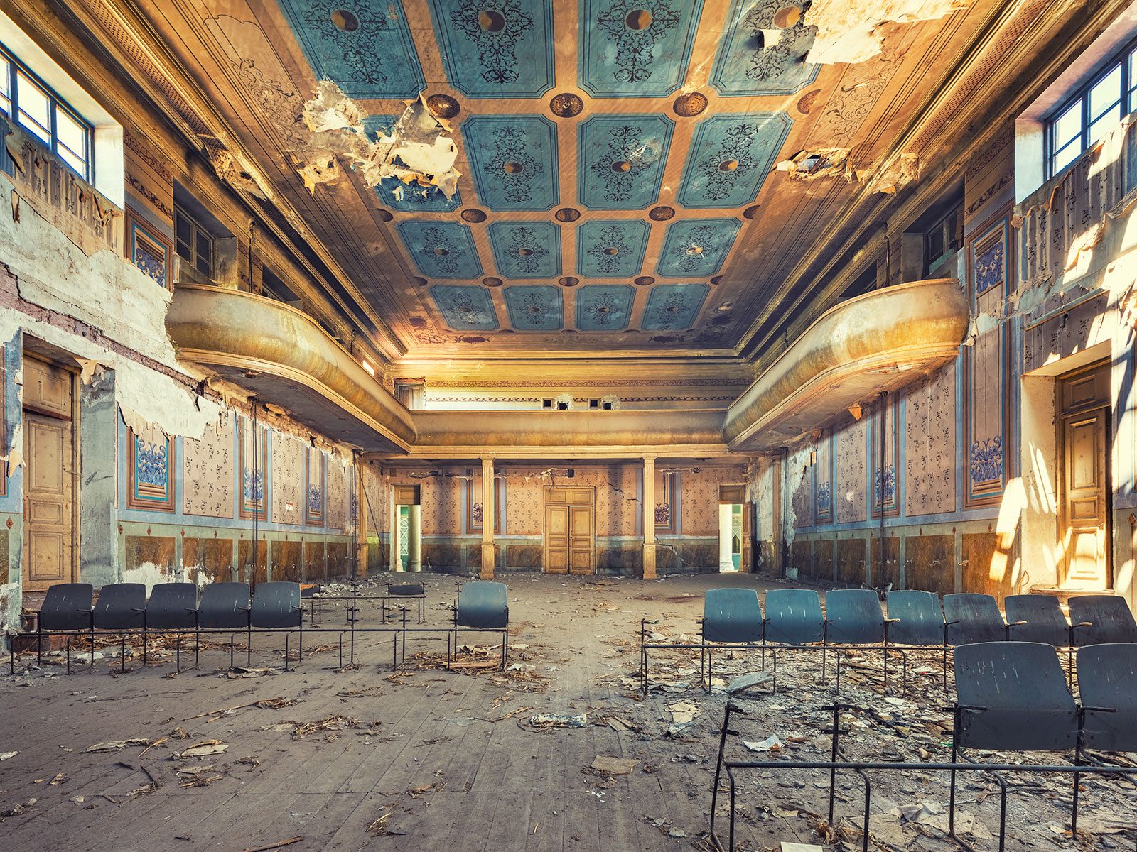 Decaying hall with gilded balconies and a blue coffered ceiling in a house of culture in Georgia
