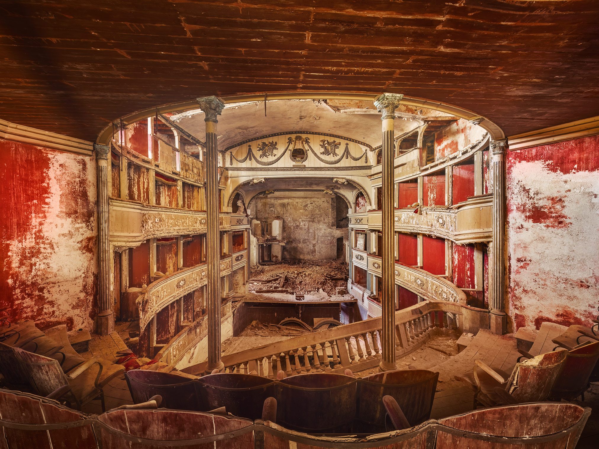 Theatre hall with coffered ceiling, chandelier, and red curtain in Italy