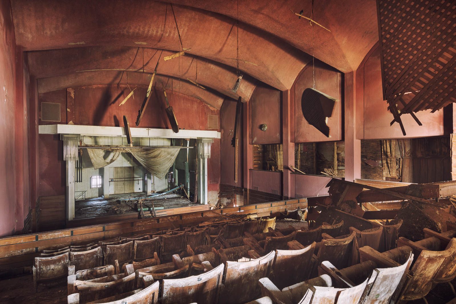 Decaying theatre with a pink vaulted ceiling and ruined rows of seats in Lombardy, Italy