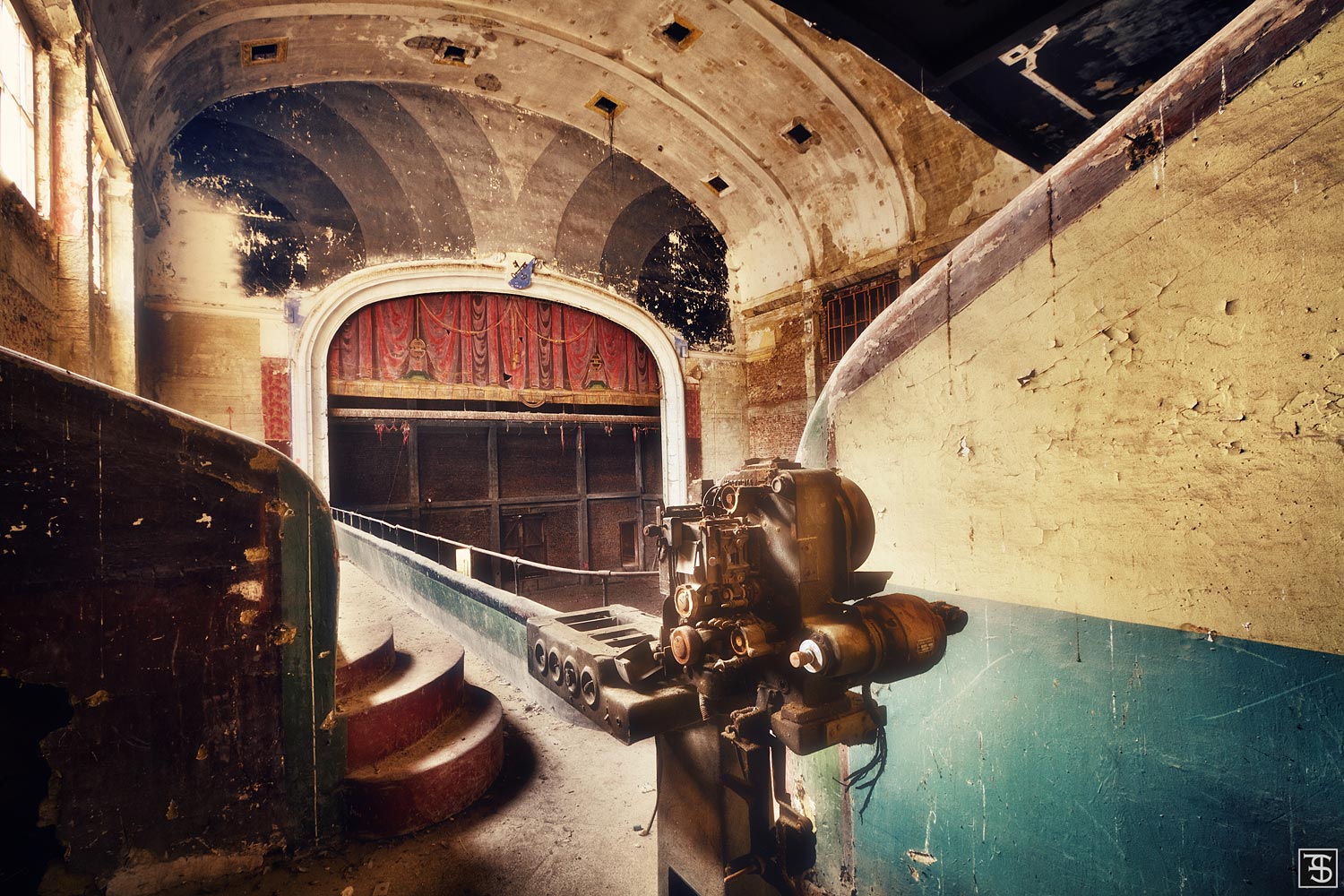 Derelict theatre with a vaulted ceiling, a film projector, and a red curtain in Belgium
