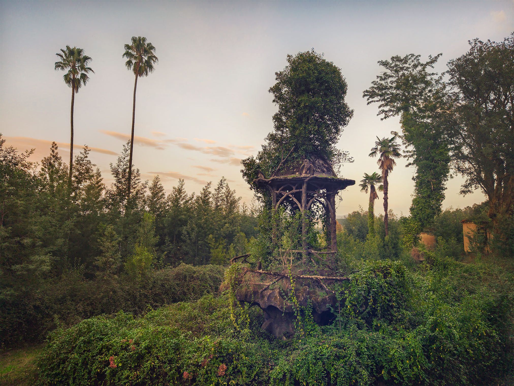 Pavillon von einem Baum überwachsen in einem vergessenen Garten in Portugal