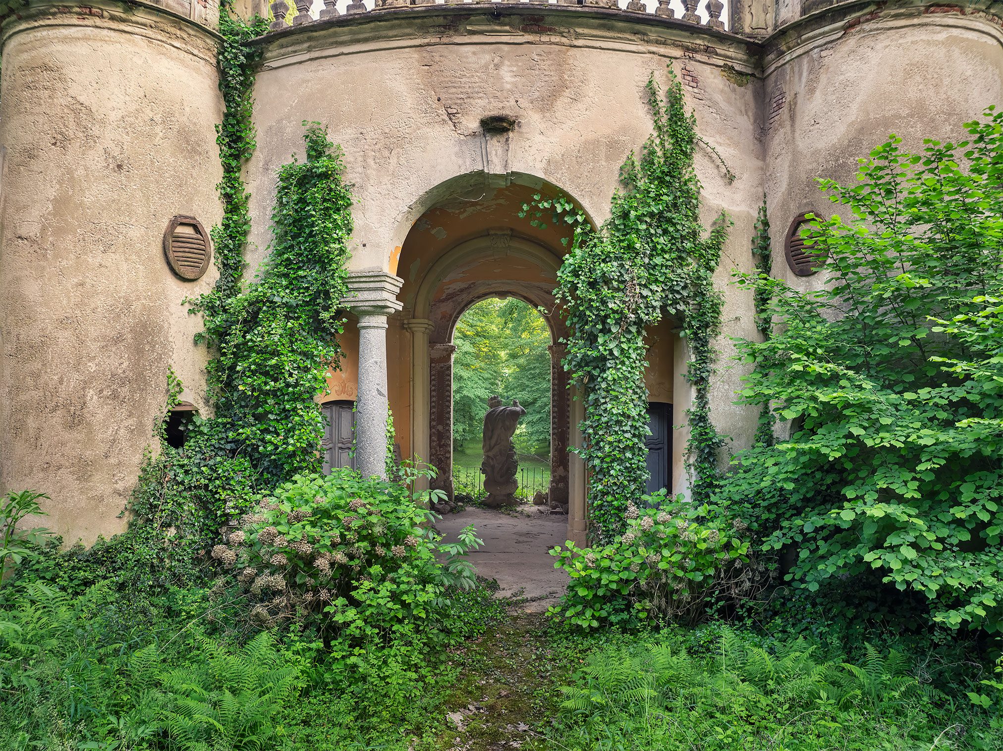 Von Efeu überwachsener Torbogen einer verlassenen Villa in Italien