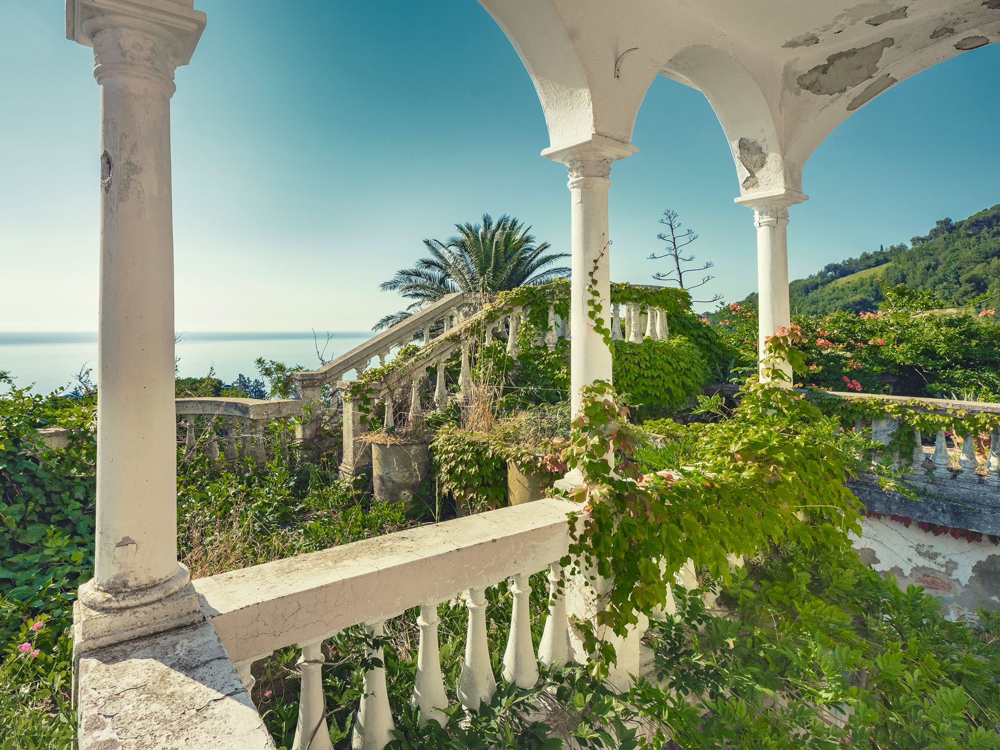 Loggia mit weißen Säulen und Meerblick in einem verlassenen Hotel in Italien