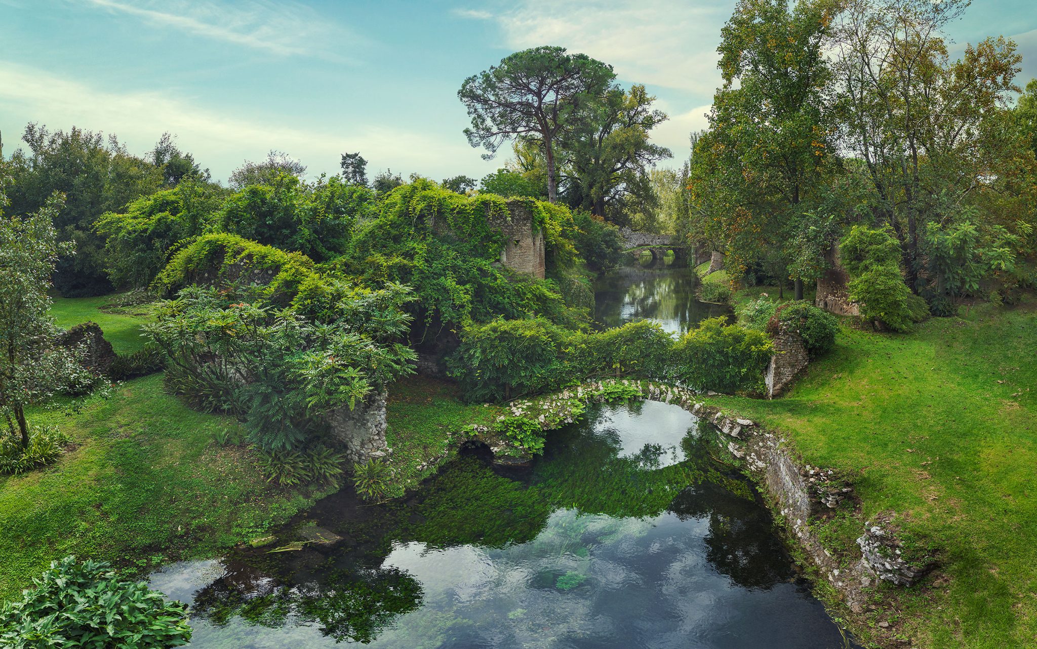 Efeuüberwachsener Ruinenturm an einem Kanal in einem Landschaftsgarten in Italien
