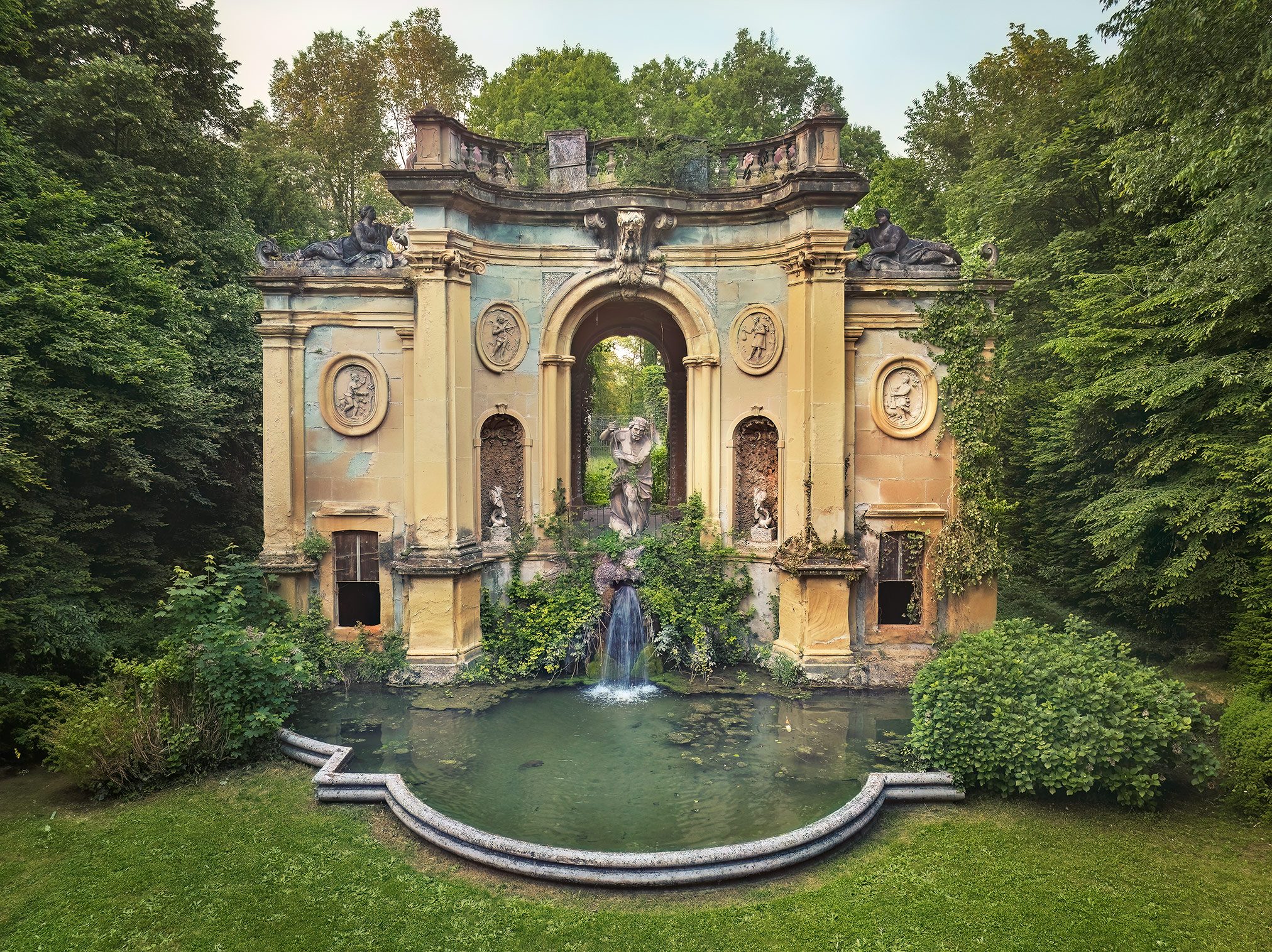 Barockes Nymphäum mit Wasserfall und Statuen in einem Park in Italien