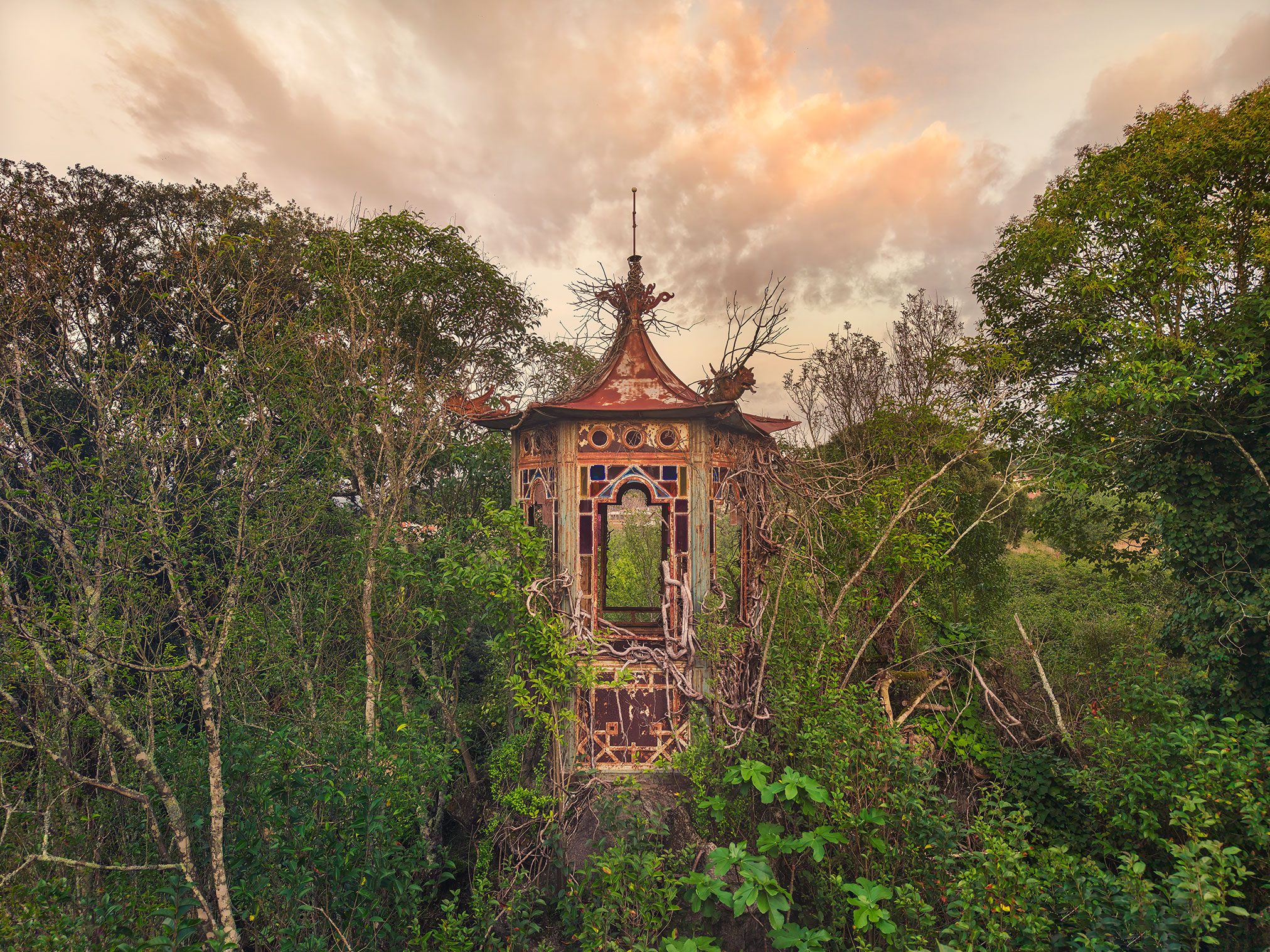 Rusted pagoda like pavilion with stained glass in an overgrown garden in Portugal
