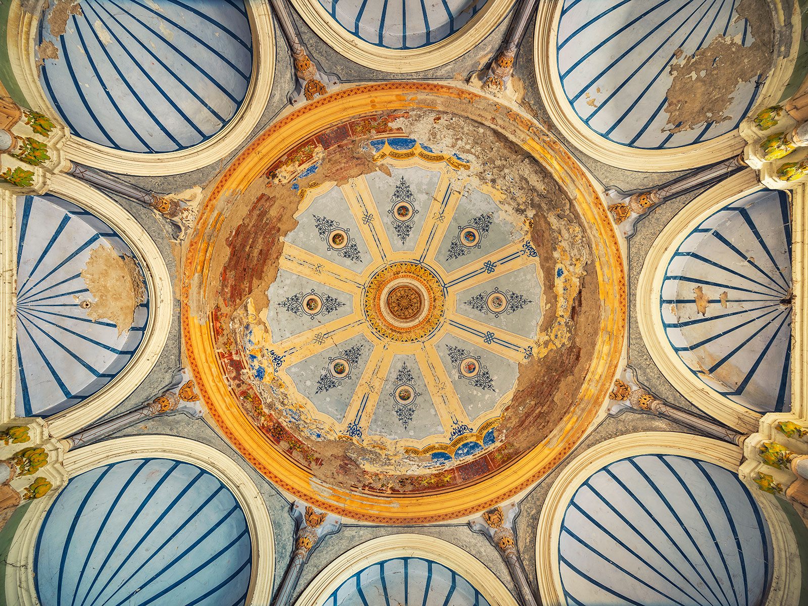 A domed ceiling with blue coffers and a weathered rosette motif in a spa town in Romania