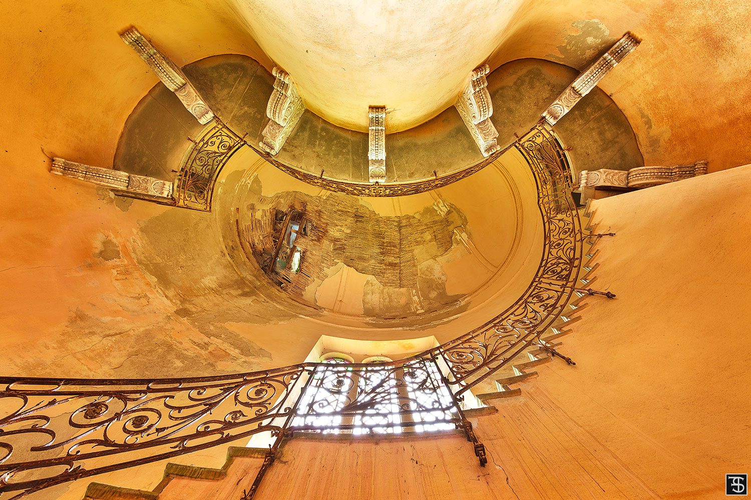 An oval stairwell with a wrought-iron railing in an abandoned Art Nouveau villa in Italy