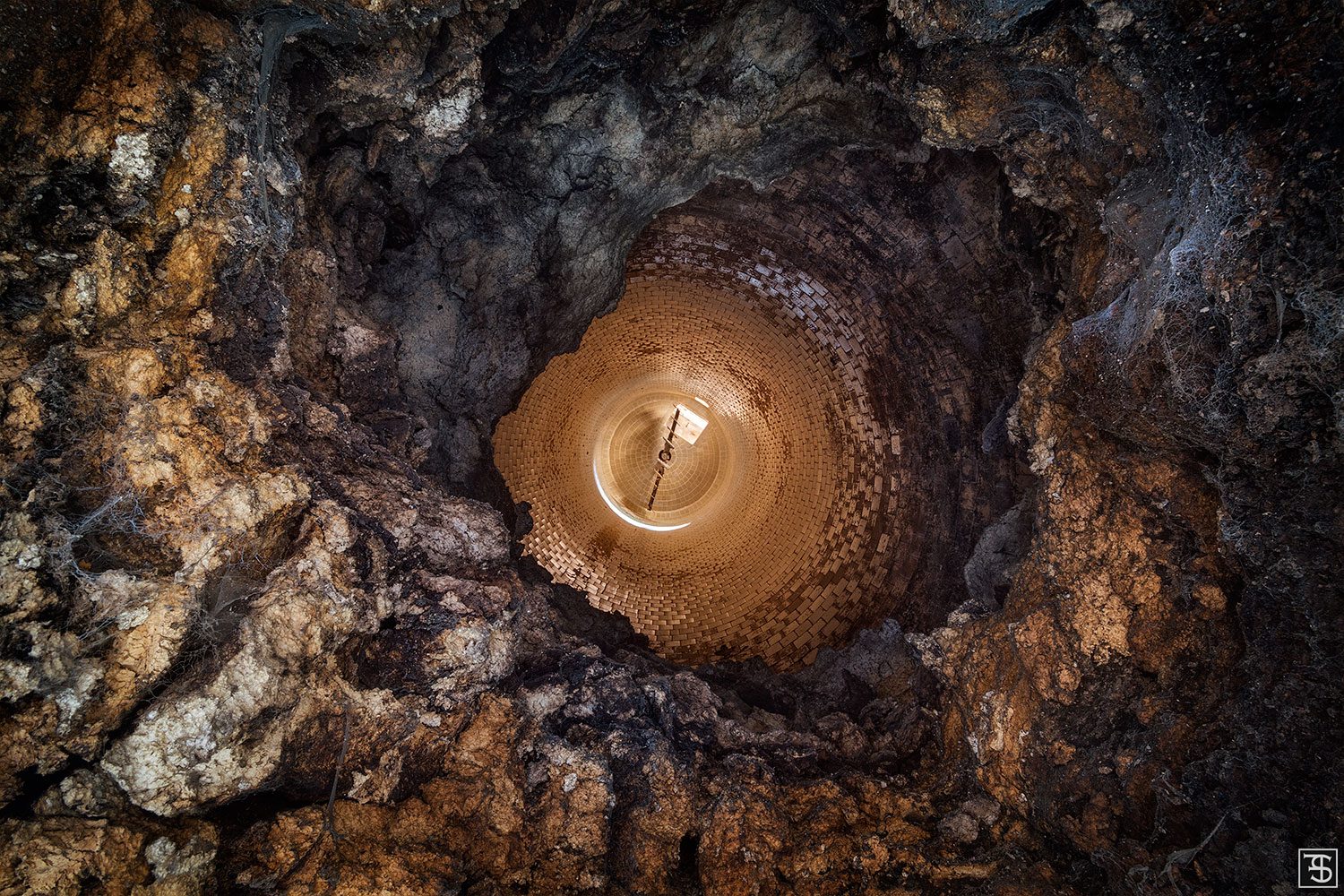 A view down a silo shaft with a rough stone wall in an old cement works in Italy